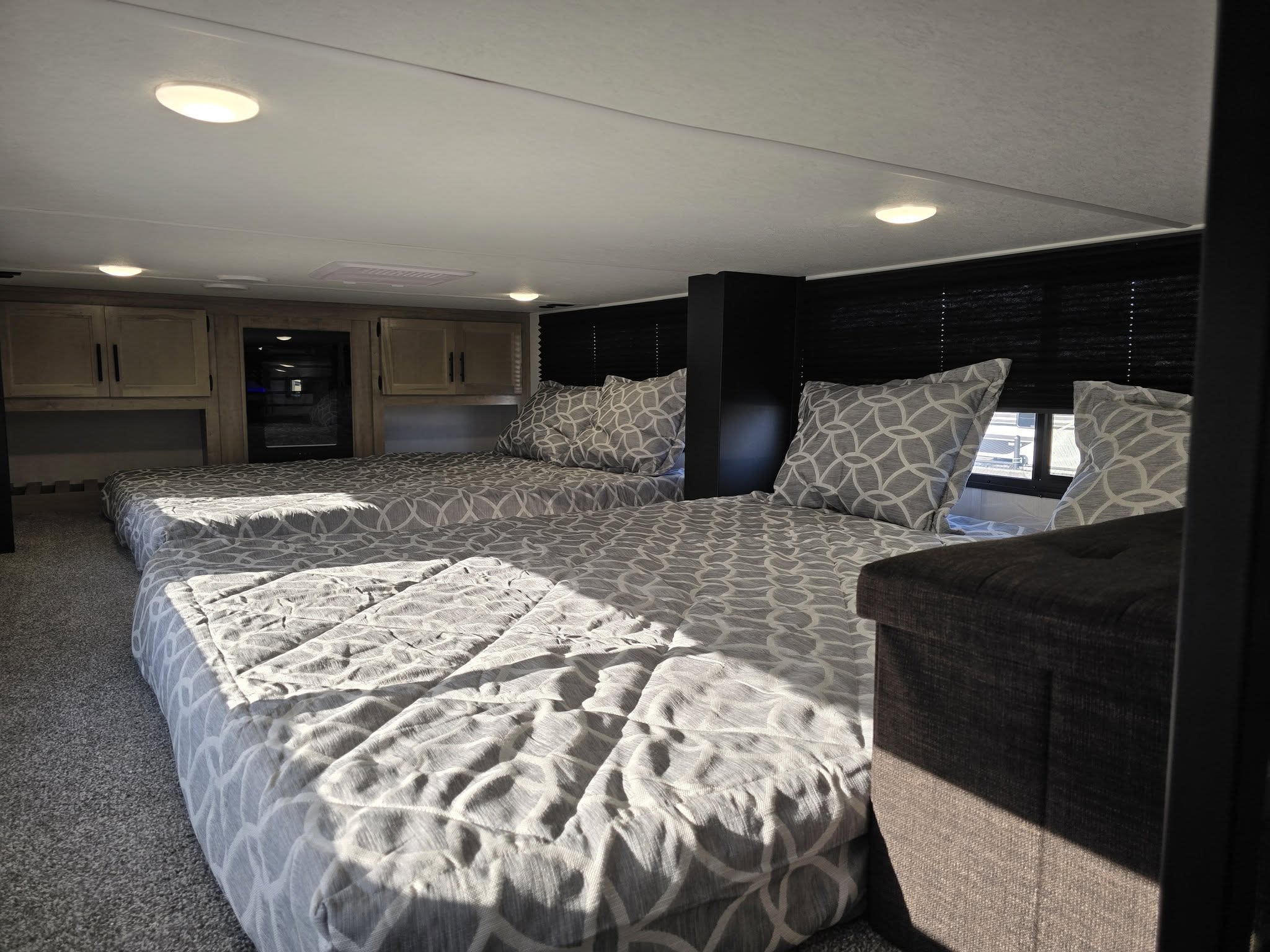 Experience comfort on wheels! This RV rental features a cozy sleeping area with two beds, overhead cabinets, and ambient lighting.. Forest River Cherokee Timberwolf 2025