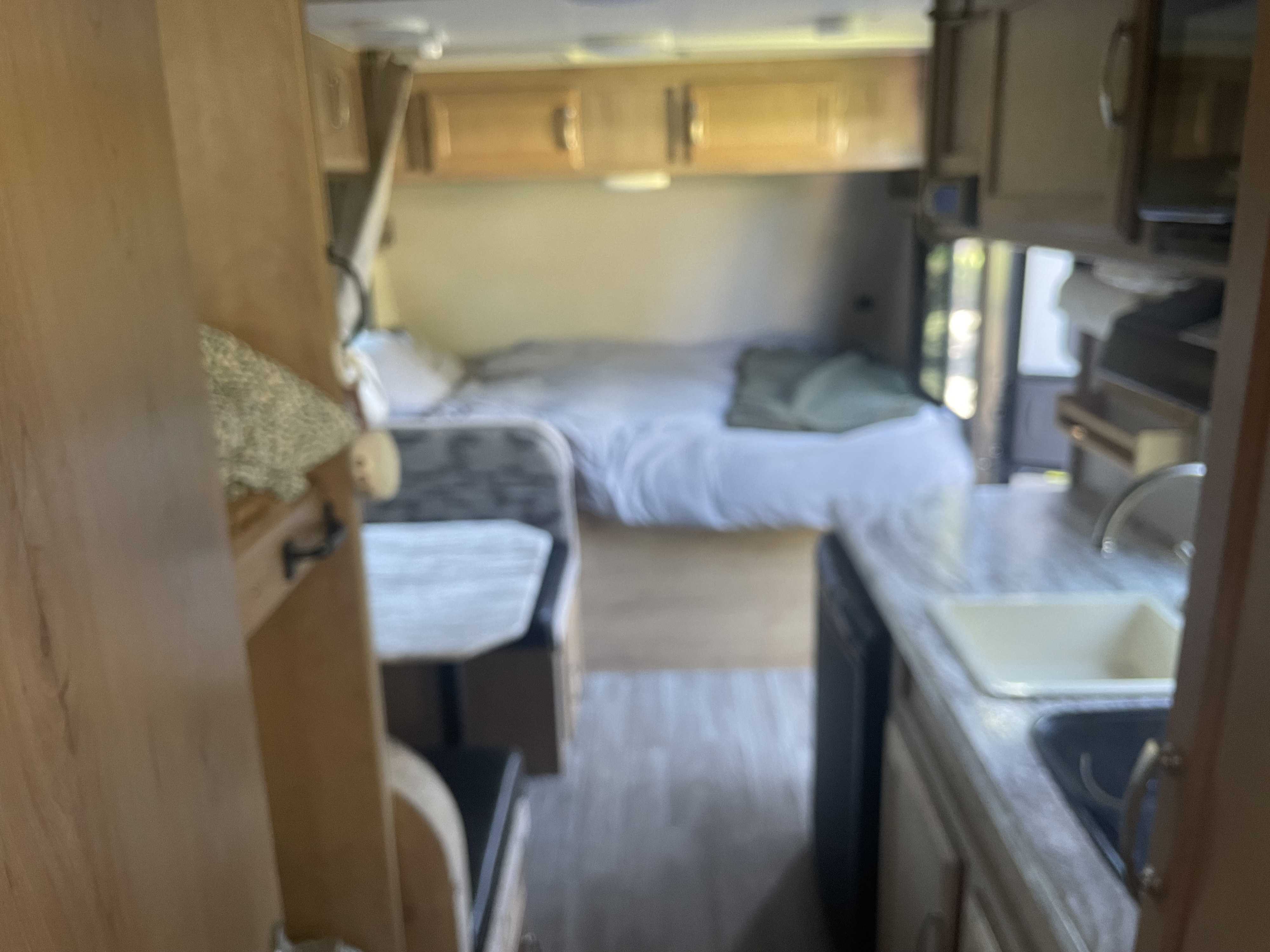Cozy rv rental interior with a bed, kitchen, and dinette visible, providing a glimpse of a compact living space.. Winnebago Micro Minnie 1700BH 2019
