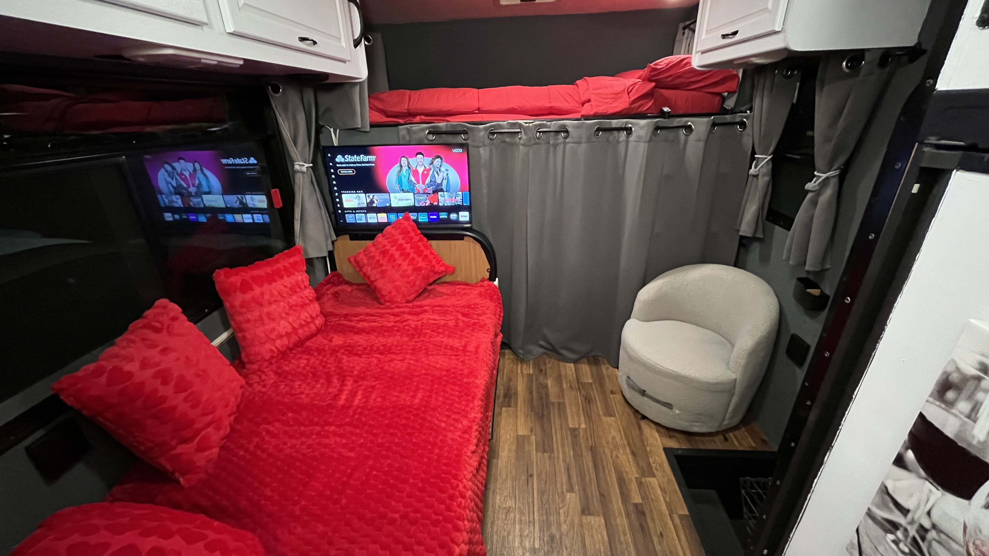 Explore this cozy RV rental featuring a plush red bed, smart TV, upper bunk, and comfy swivel chair for relaxation.. Thor Majestic 2017