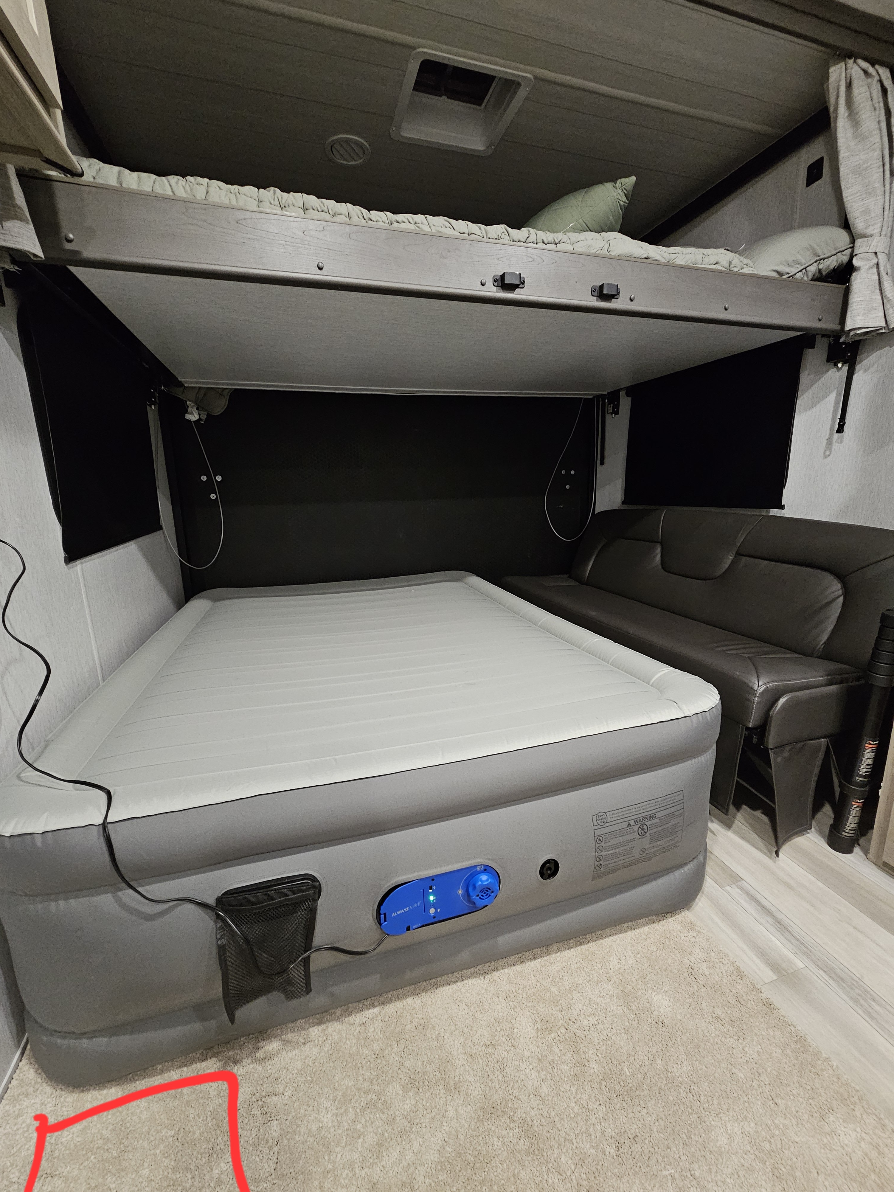 RV rental bunk area featuring a large air mattress on the floor, a bunk bed above, and a comfortable sofa.. Forest River Sandstorm 2024