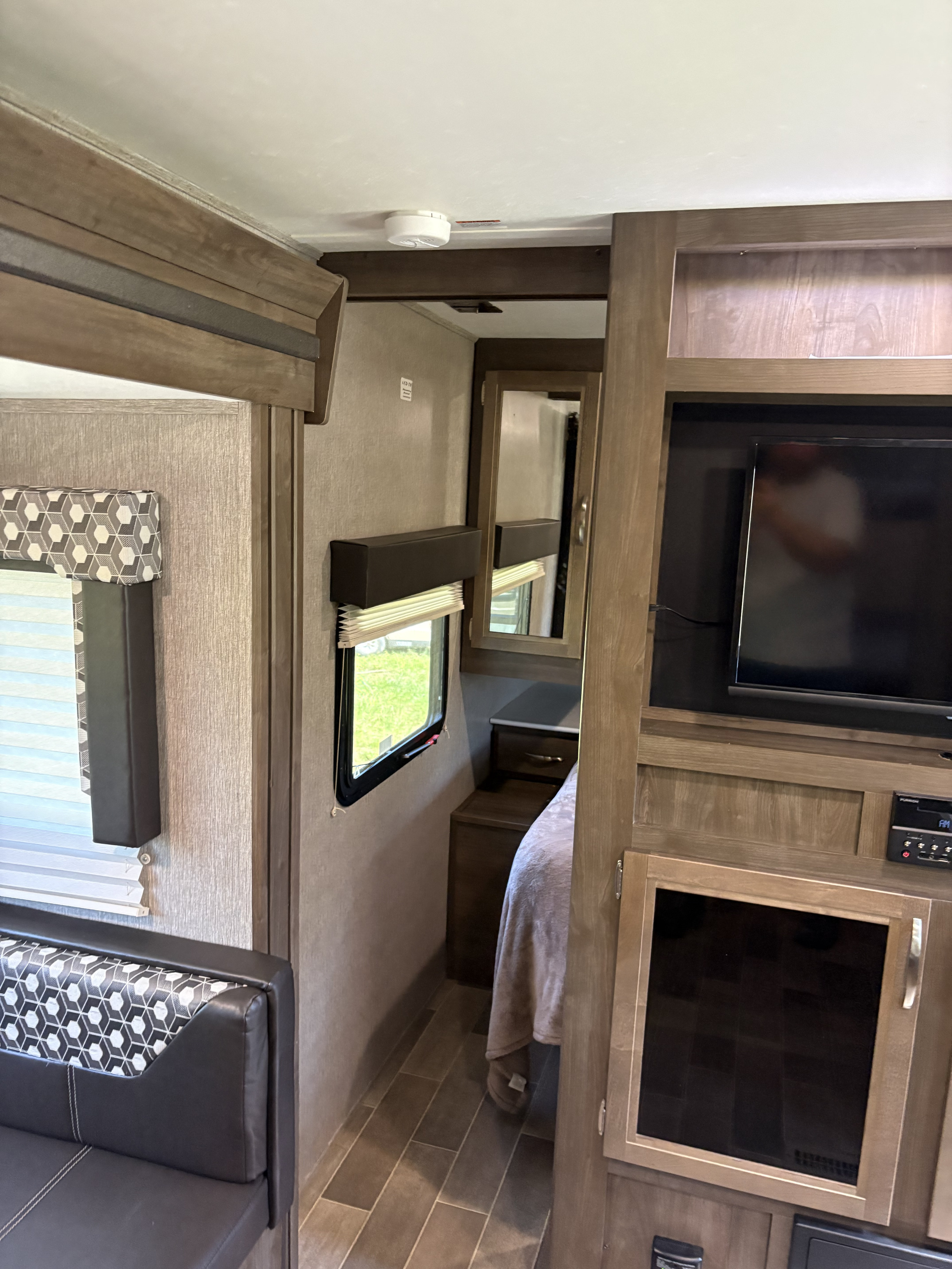 Interior of an RV rental showing the living area with a couch, entertainment center, and a hallway leading to the bedroom.. Dutchmen Coleman Light 2019