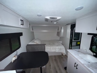 Light-filled rv rental interior: features a cozy bed, dinette, small kitchen, and overhead cabinets. Ideal for travel.. Jayco Jay Feather Air SL 2025