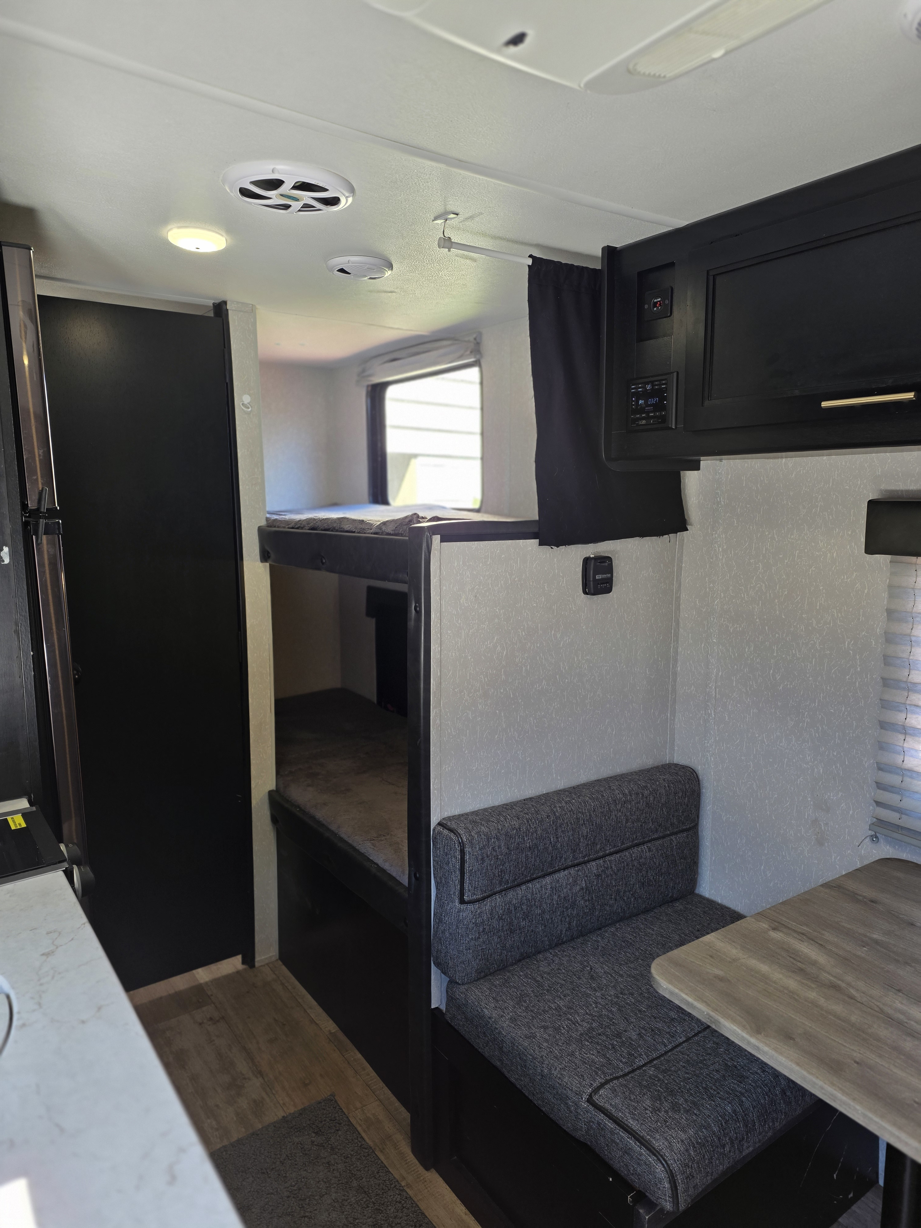 RV rental interior: bunk beds on left, dinette with table & seating on right, compact kitchen. Functional camper living space.. Forest River Cherokee Wolf Pup 2022