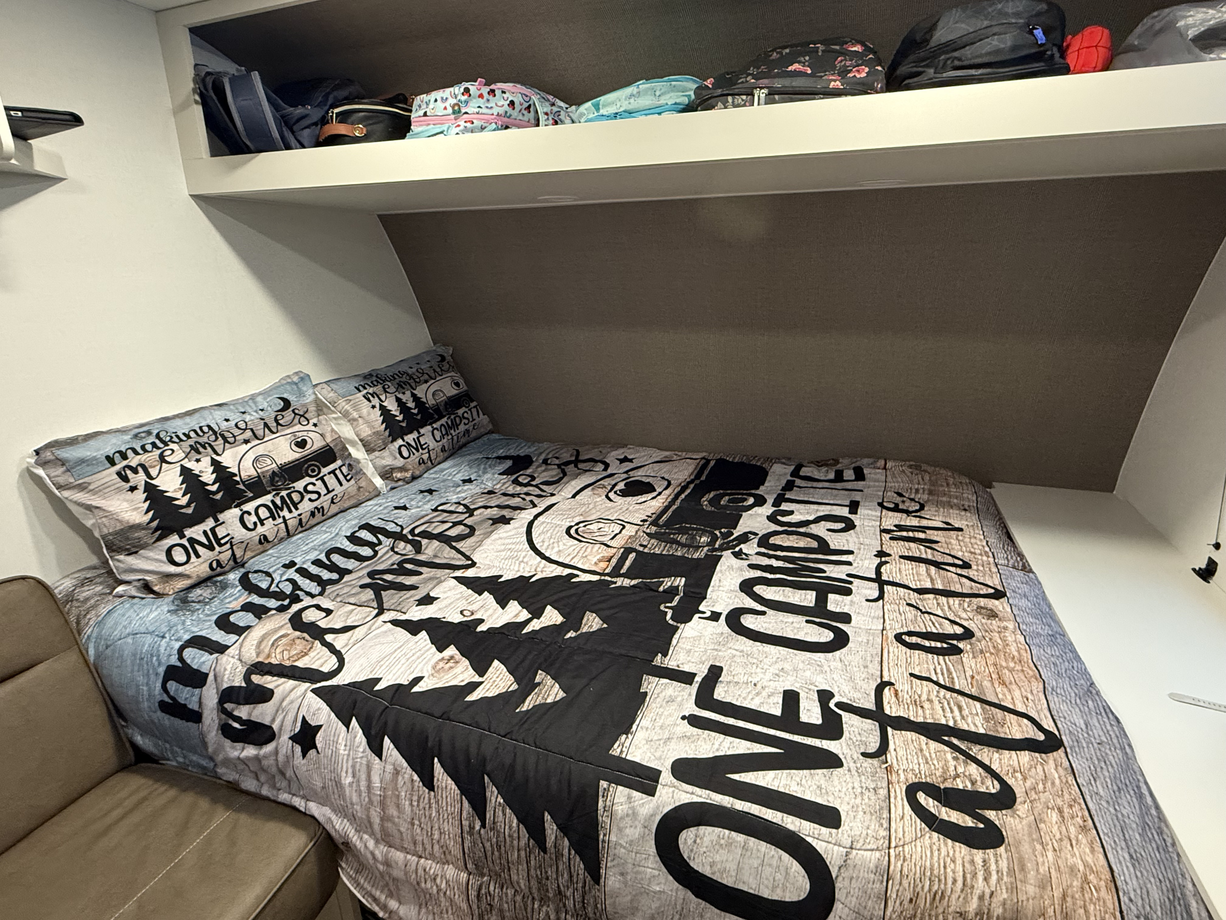 Cozy RV rental bedroom with "making memories one campsite at a time" bedding and overhead storage for a fun trip.. Transcend One 151BH 2026