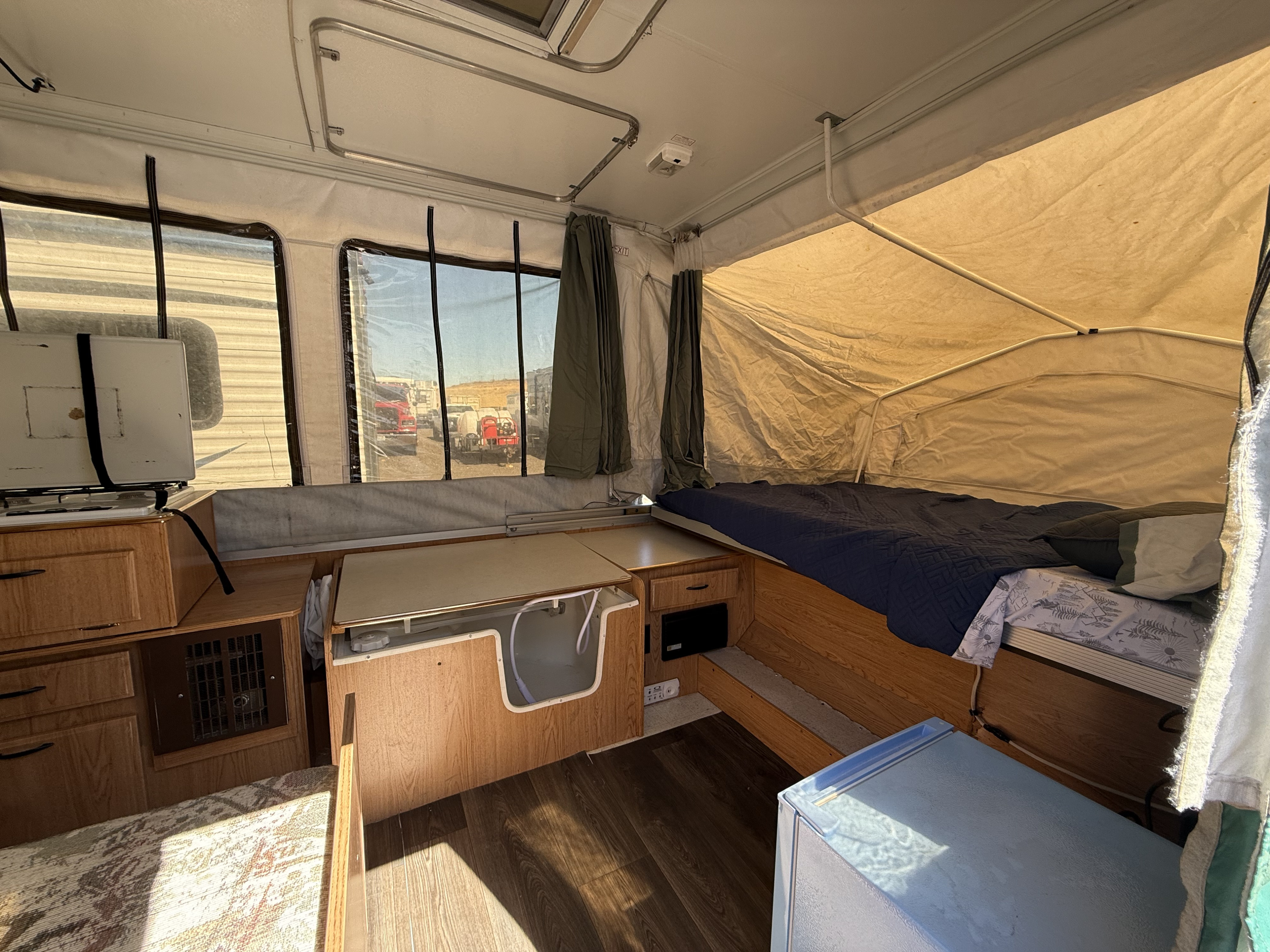 Compact interior of an RV rental pop-up camper with bed, kitchenette, and dining space.. Forest River Rockwood Freedom 2003