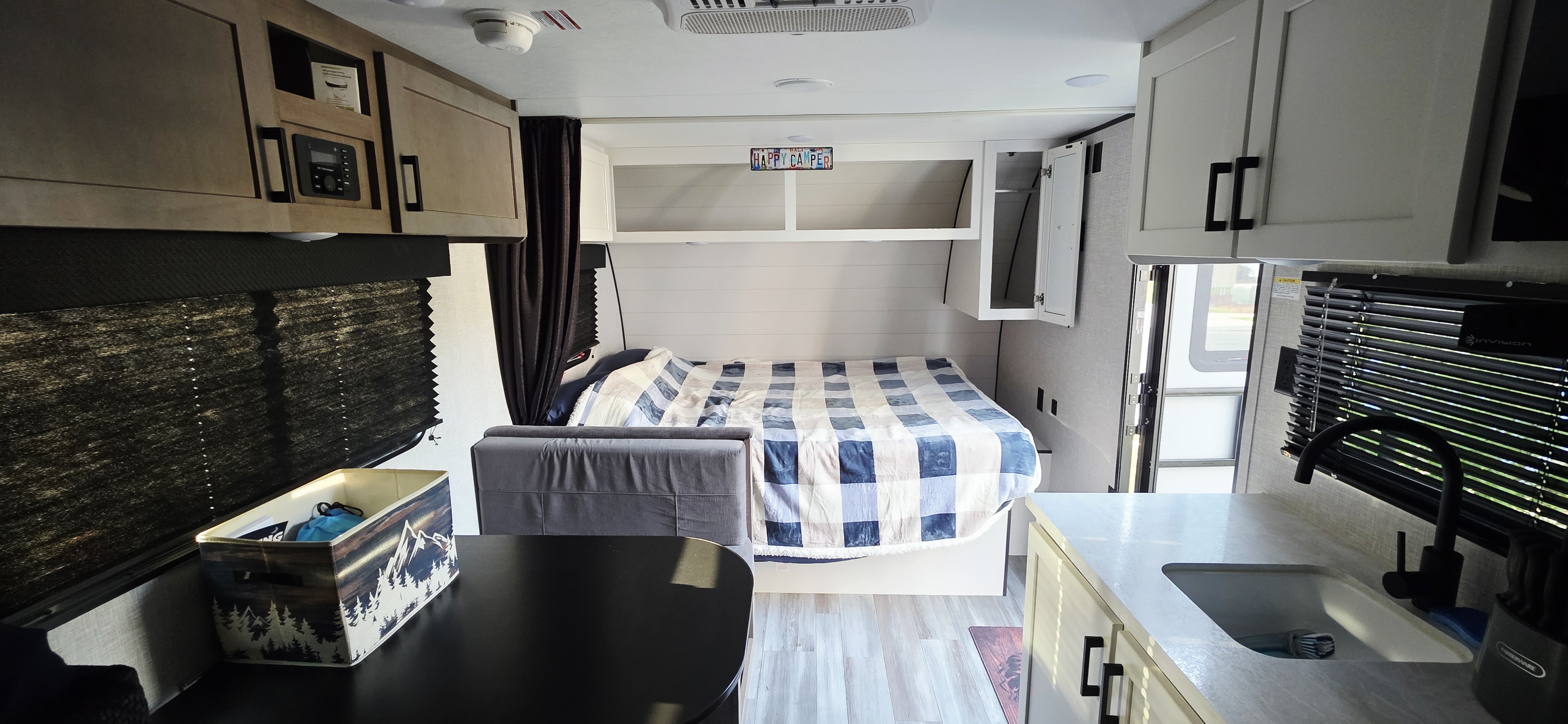 RV rental interior: cozy bed, dining area, and compact kitchen with sink. Overhead cabinets & blinds complete the welcoming space.. Jayco Jay Flight SLX 2025