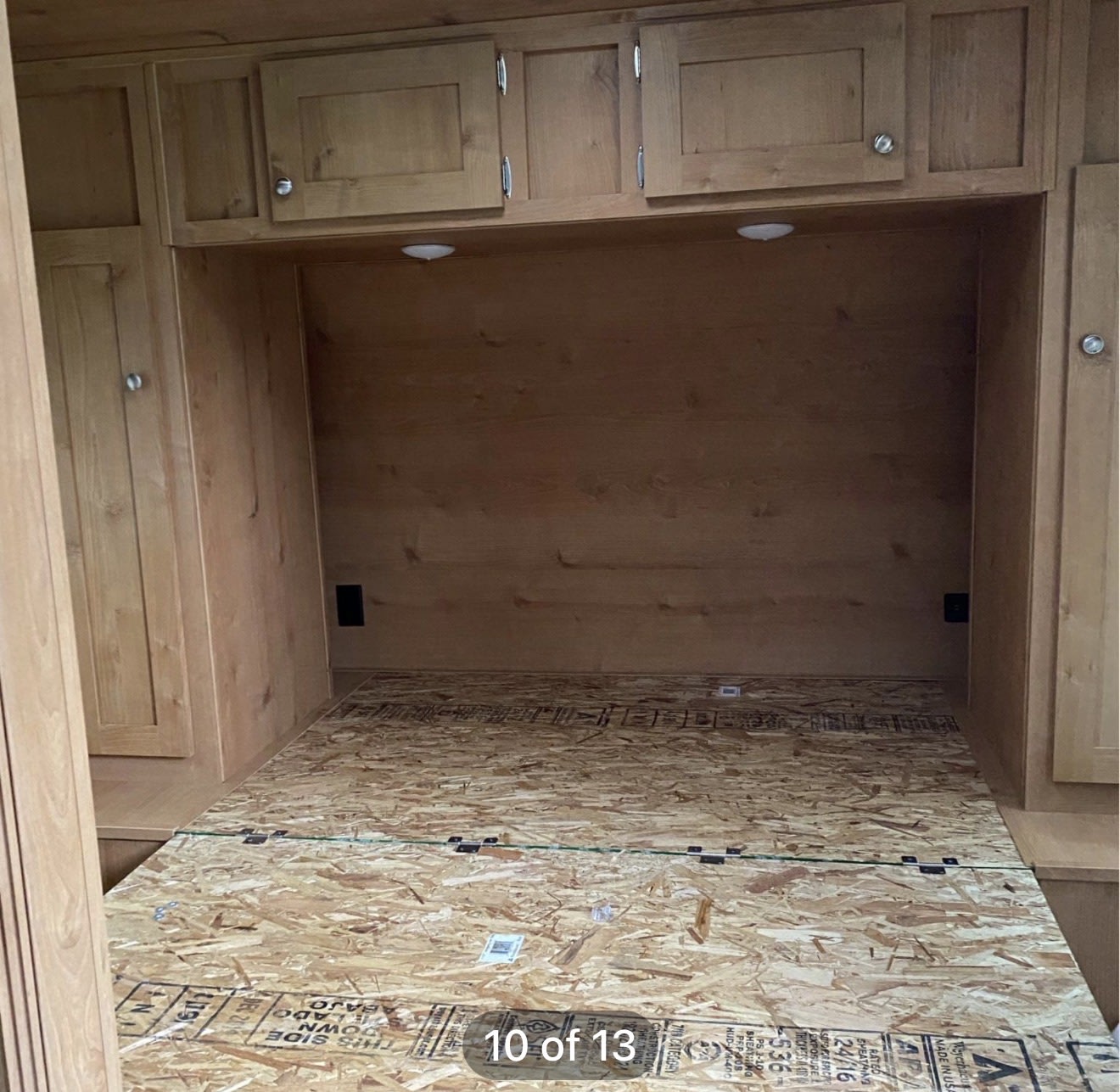 RV rental interior showing a bedroom with wooden cabinets and an OSB bed platform, awaiting a mattress.. Riverside RV Retro 2020
