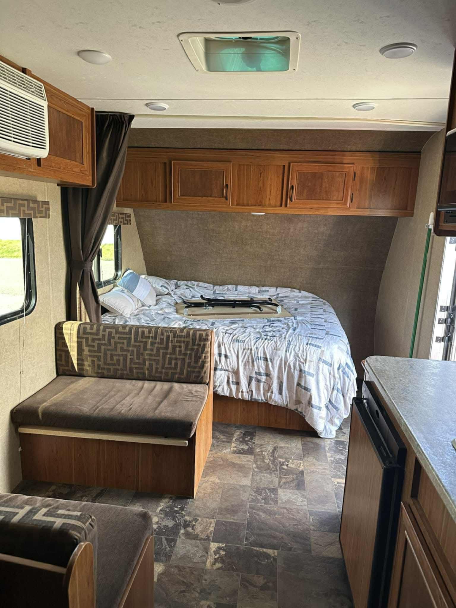Cozy RV rental interior: view of the bed, dinette, and kitchenette with wooden cabinets, AC unit, and tiled floor.. Starcraft AR-One Maxx 2017