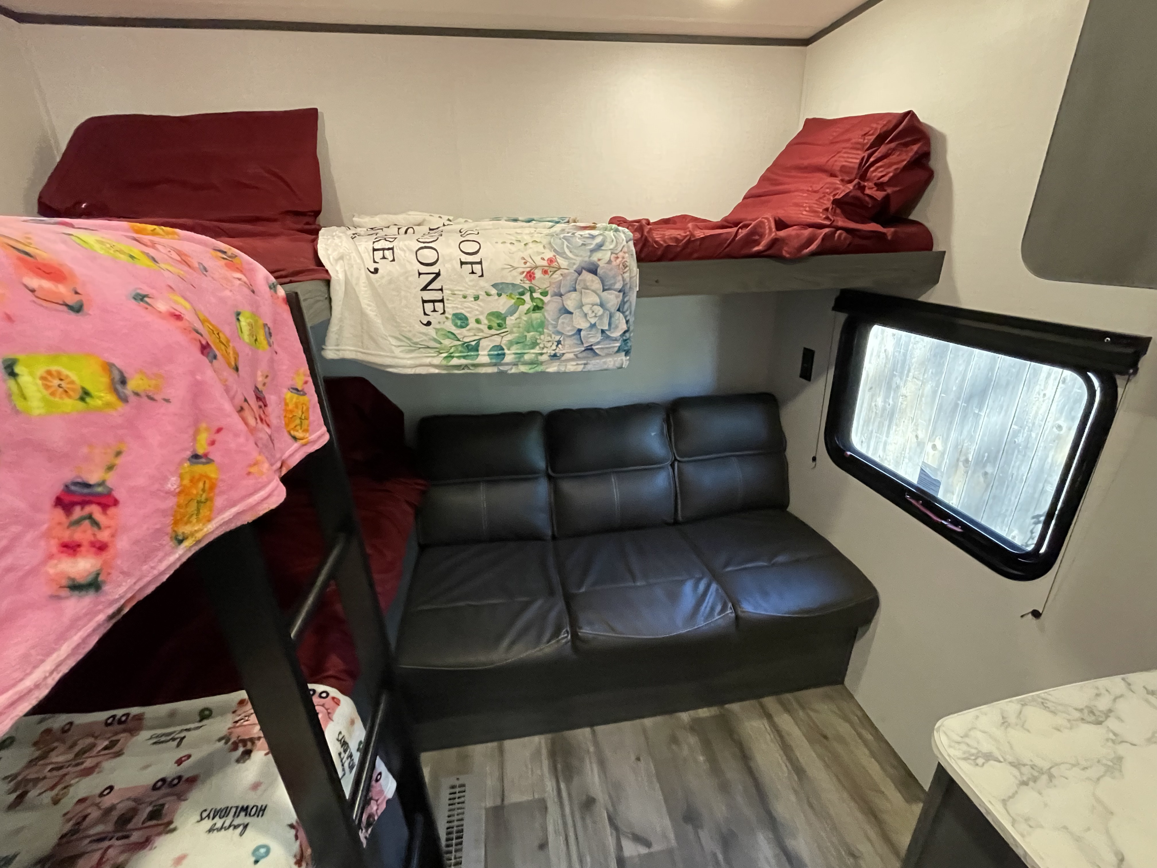 RV rental interior features cozy bunk beds with blankets, a dark sofa below, and a window, offering a compact living space.. Dutchmen Colorado 29BHC 2025