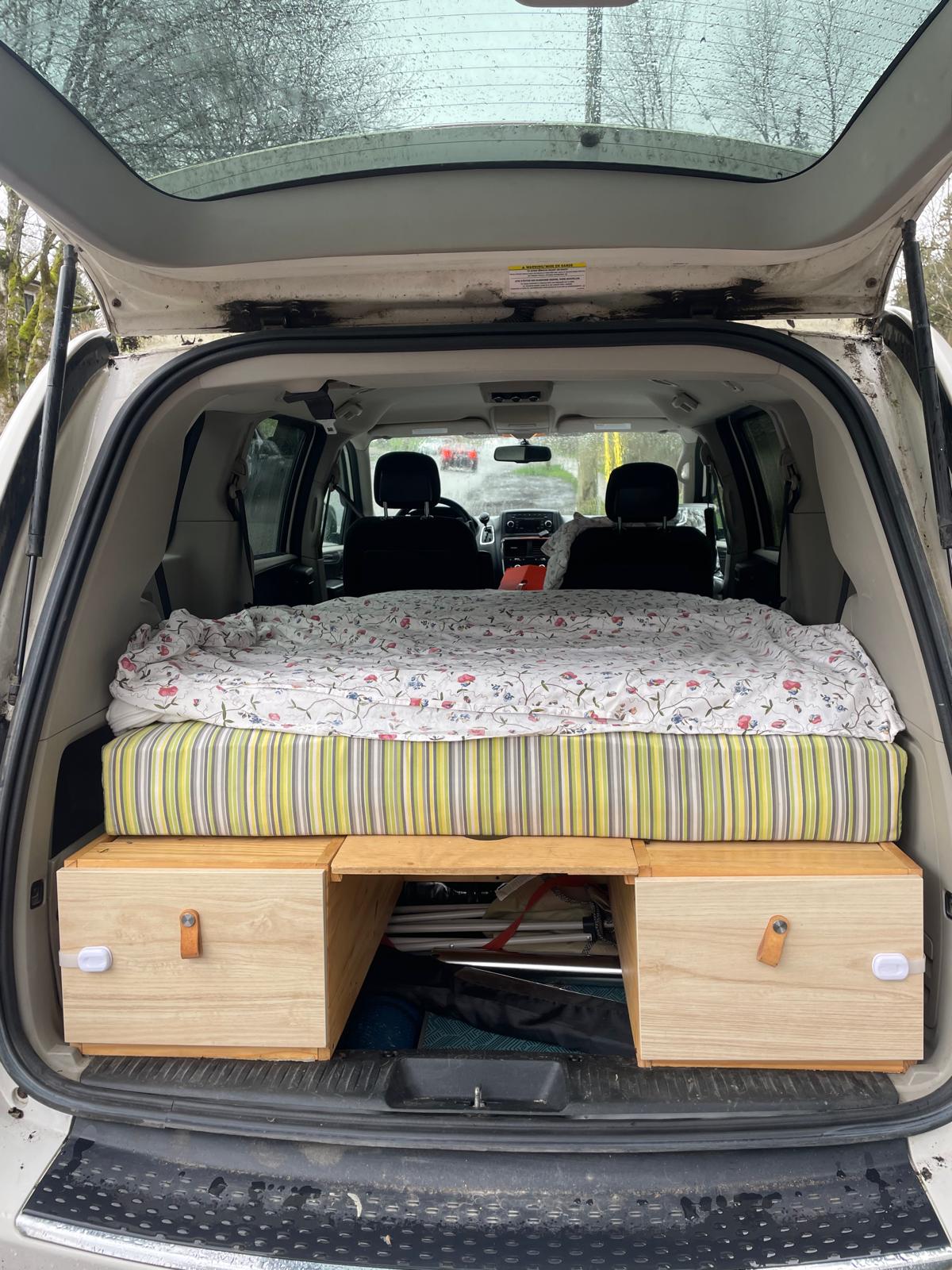RV rental alternative: Minivan conversion featuring a comfy bed with striped mattress and storage units in the trunk.. Dodge Grand Caravan 2011