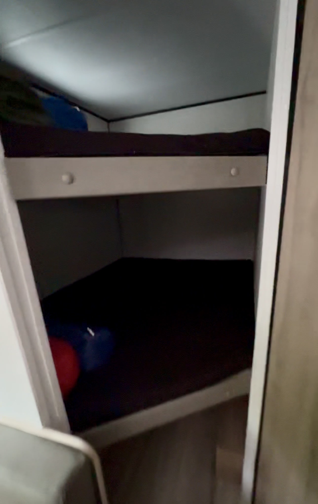 Interior of an RV rental shows two bunk beds with dark mattresses, providing a compact sleeping area.. Keystone RV Coleman 2025