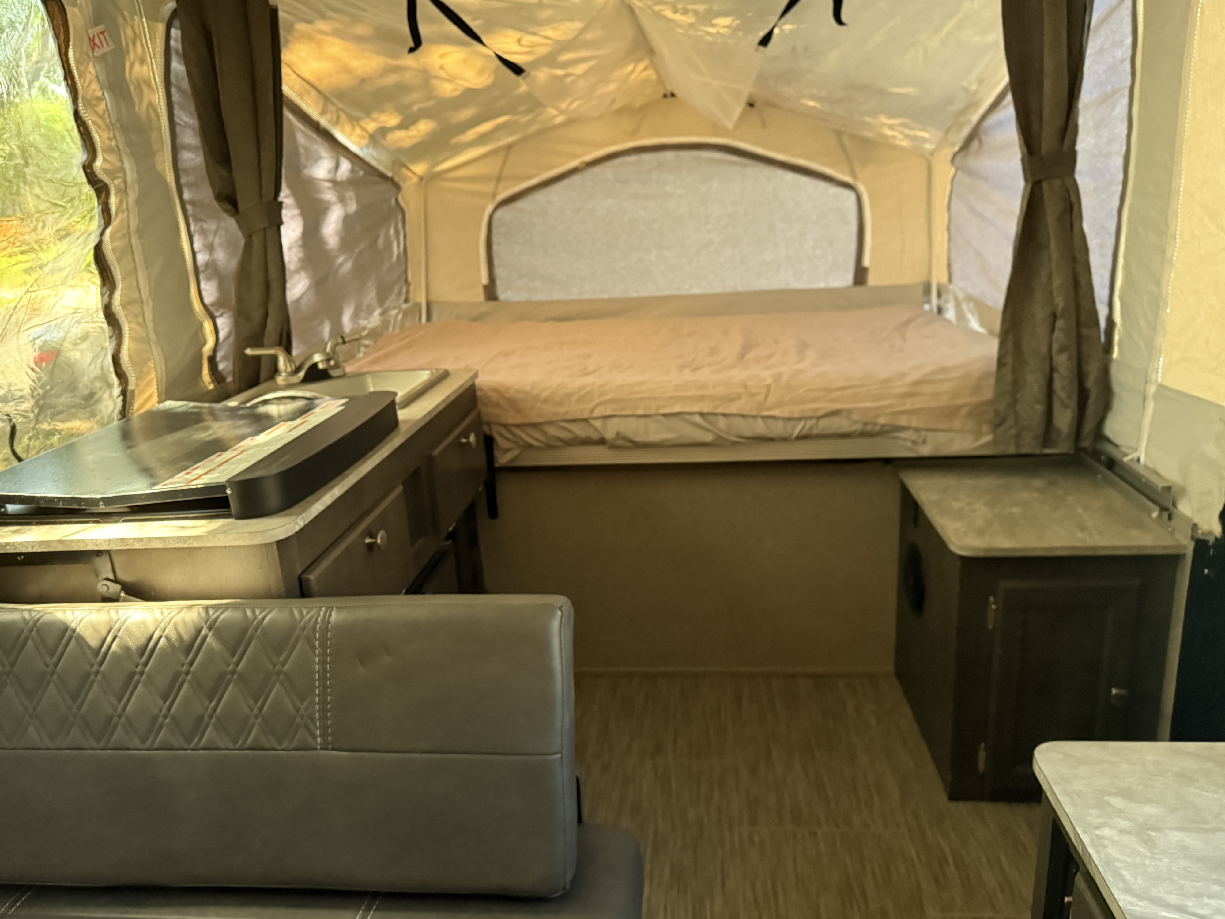 Cozy RV rental interior with a bed, kitchen sink/stove, and seating area for comfortable camping adventures.. Forest River Flagstaff 2020
