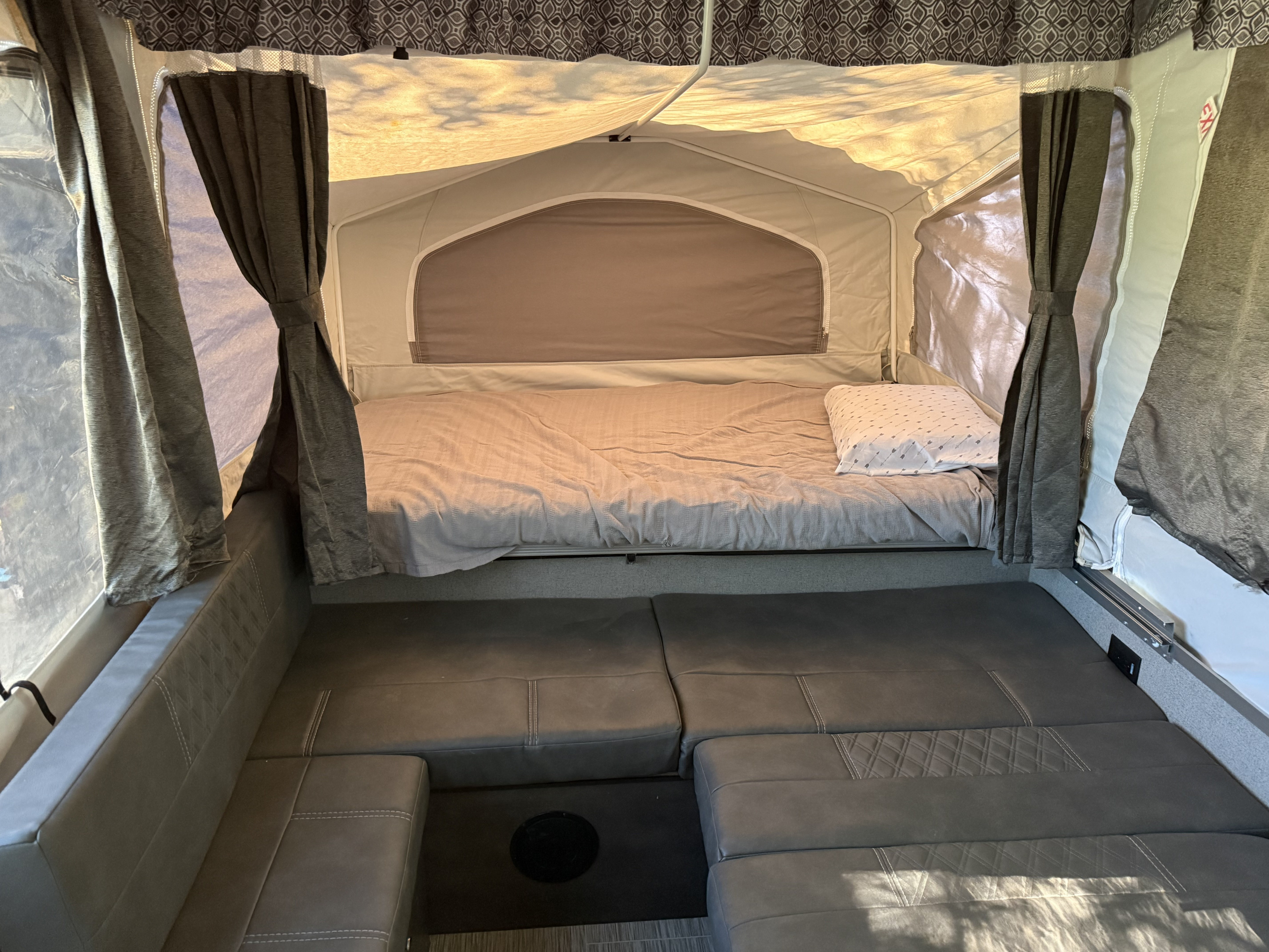 Inside this cozy RV rental pop-up camper: a bed, plush seating, and privacy curtains for comfortable camping adventures.. Forest River Flagstaff 2020