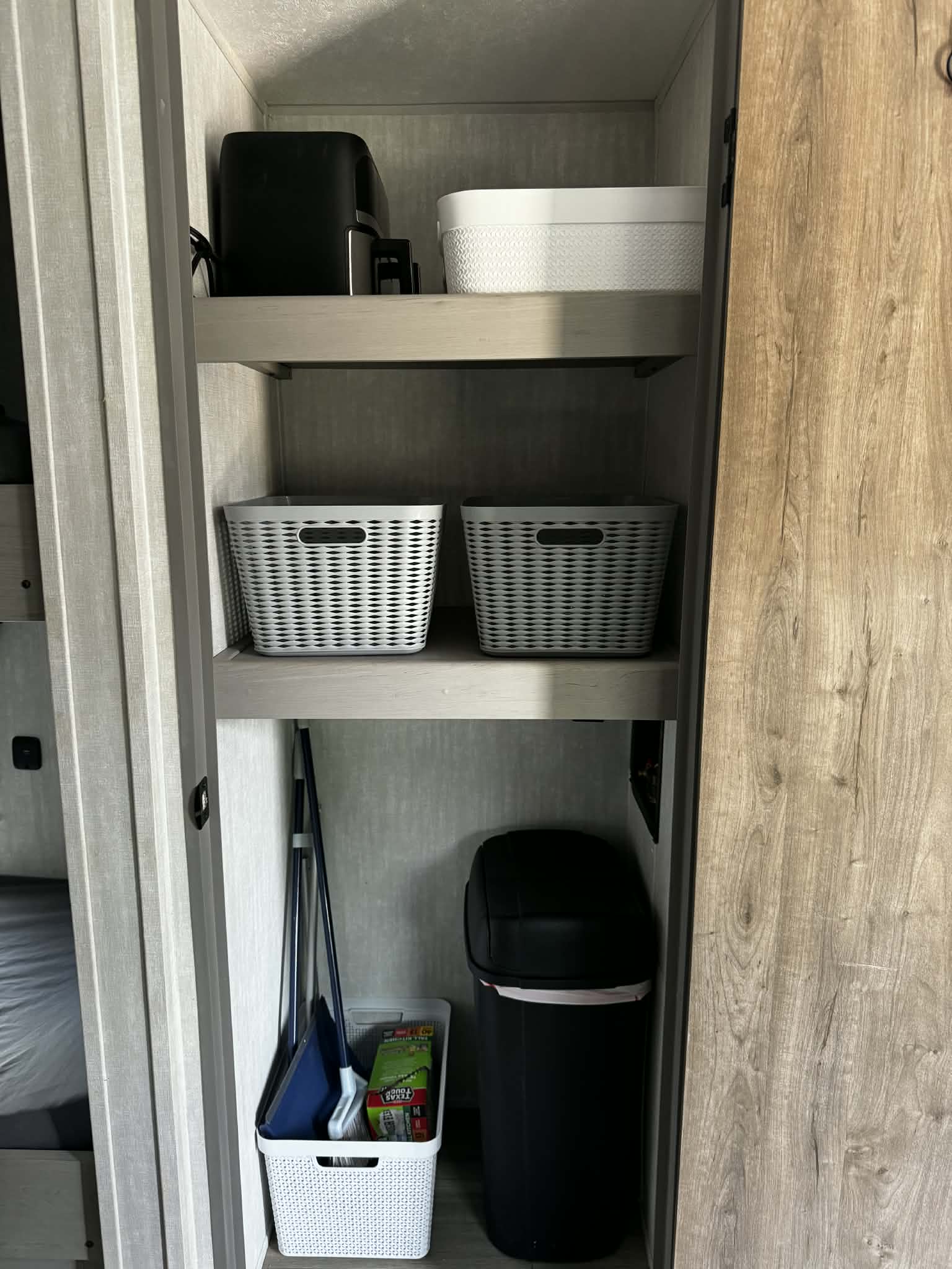 Organized RV rental closet with shelves, storage baskets, a coffee maker, trash can, and cleaning tools.. Forest River Viking 5K 2025