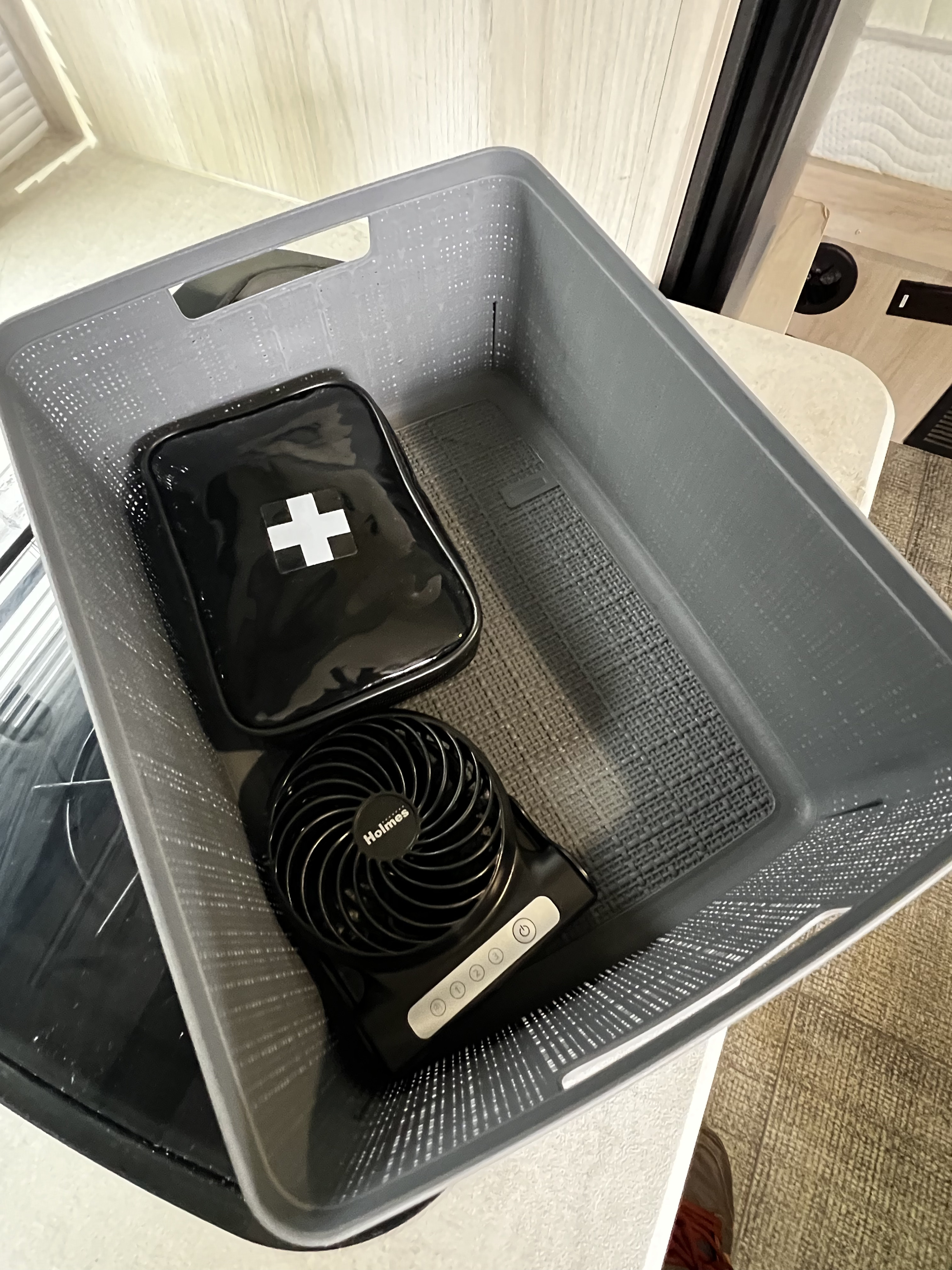 Organized RV rental supplies: a gray bin with a black first aid kit and a Holmes portable fan for your trip.. Winnebago Hike 2022