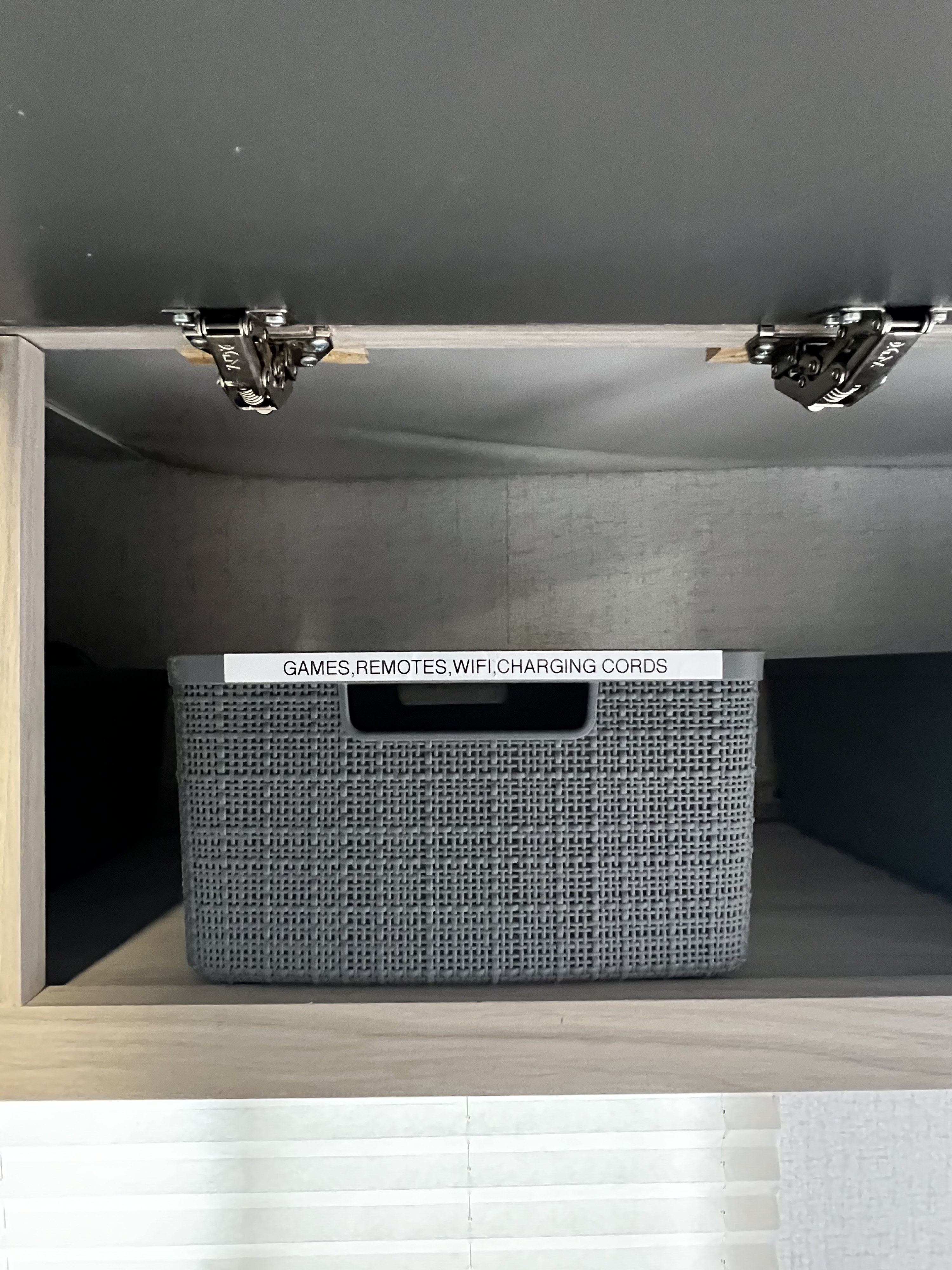 Organized RV rental cabinet. A labeled storage basket holds "GAMES, REMOTES, WIFI, CHARGING CORDS" for easy access.. Winnebago Hike 2022