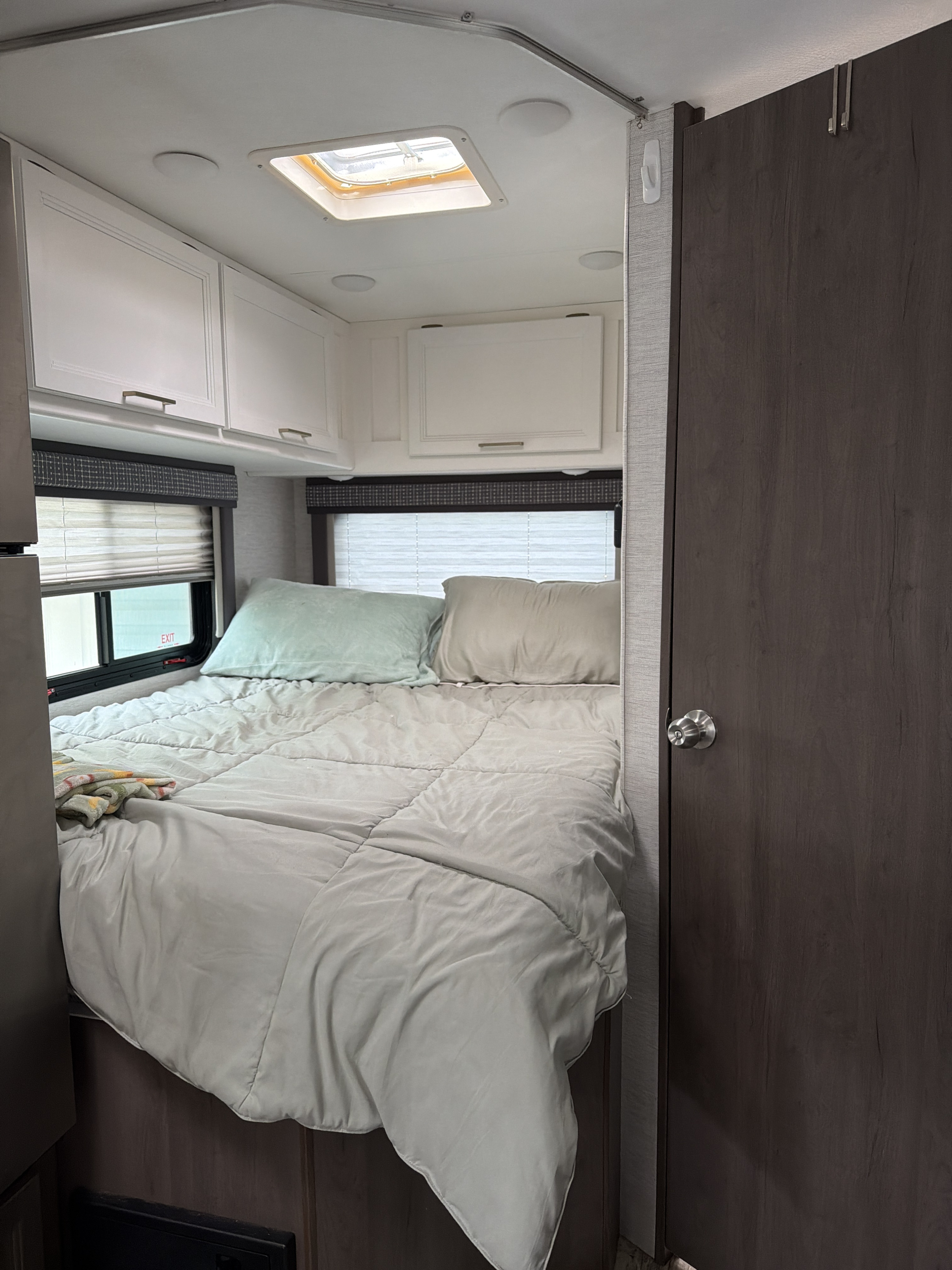 RV rental bedroom: Cozy, compact interior with bed, overhead cabinets, windows, and a ceiling skylight.. Thor Chateau 2024