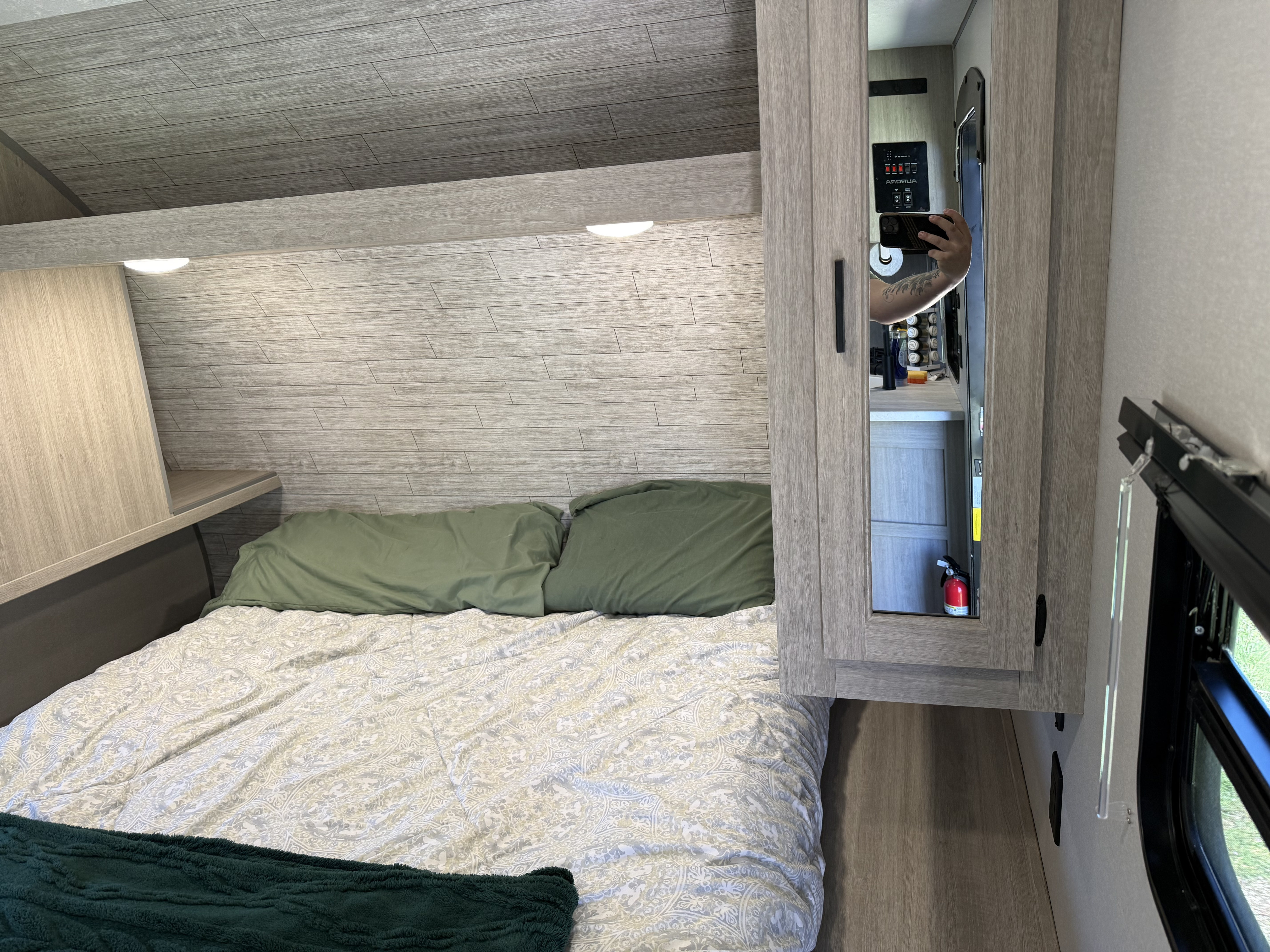 Cozy rv rental bedroom features a comfortable bed, modern wood-look interior, and built-in mirrored storage.. Forest River Aurora Aurora Light 2025