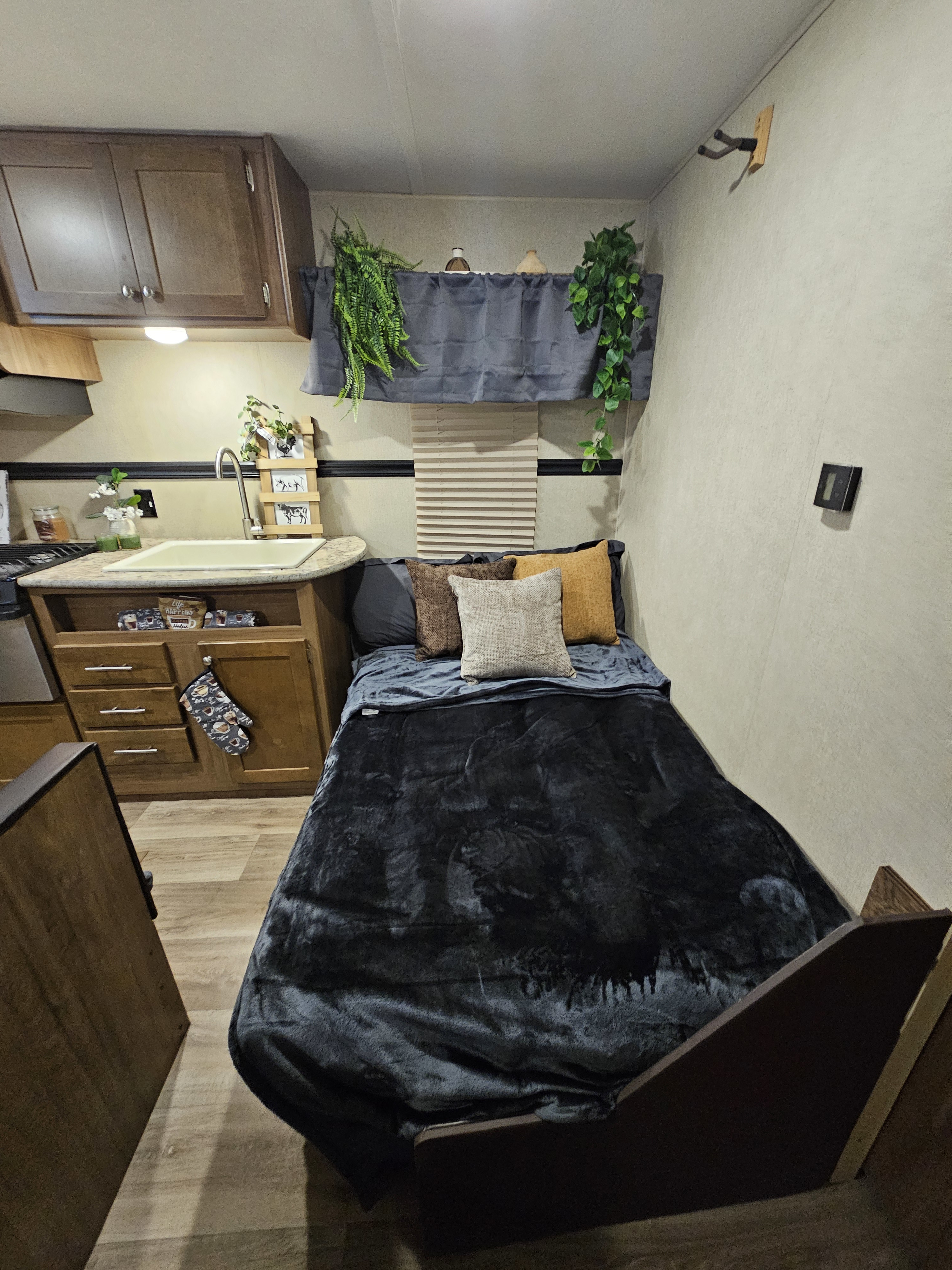 Cozy RV rental interior: compact bed with colorful pillows, next to a small kitchen with sink & decorative plants.. Aspen Trail Aspen Trail Trailer 2018