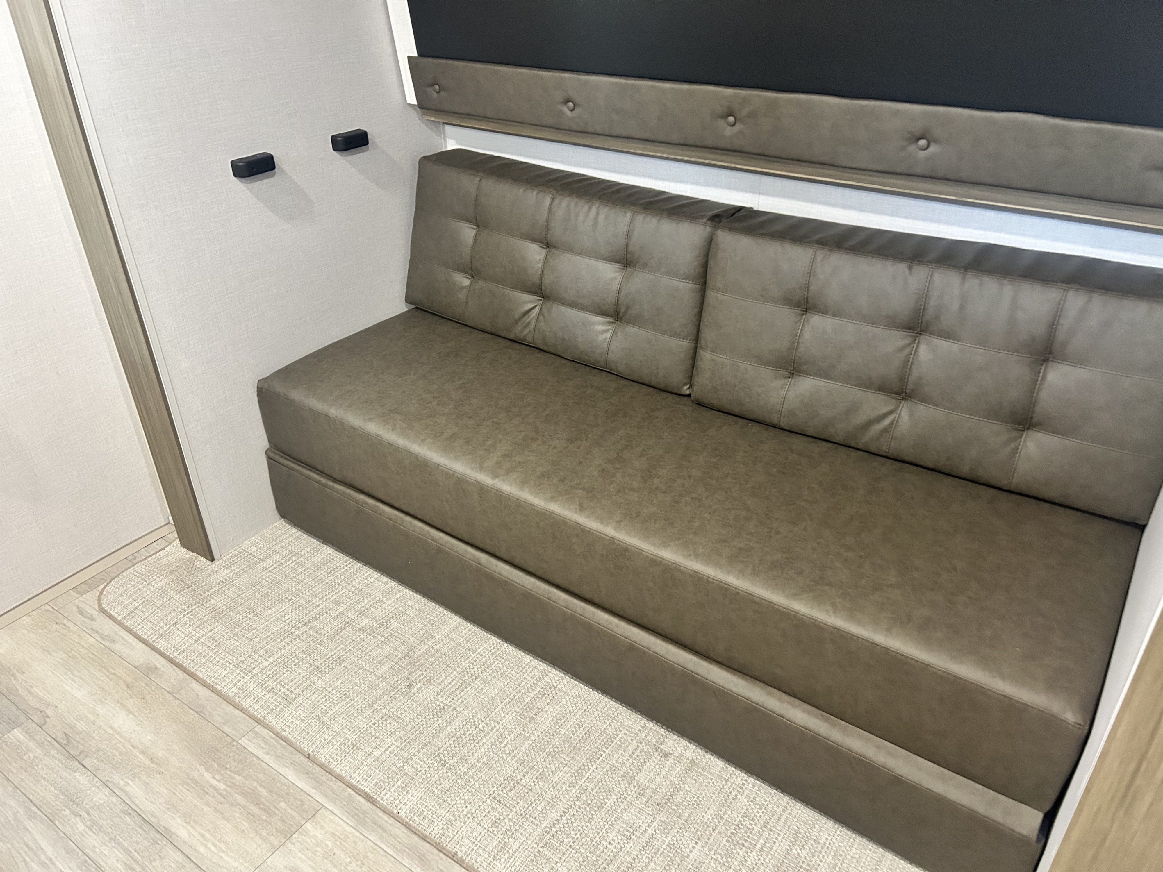Comfortable rv rental sofa bed with tufted back in a modern RV interior, featuring a pull-out base and neutral colors.. Forest River Wildwood 2025