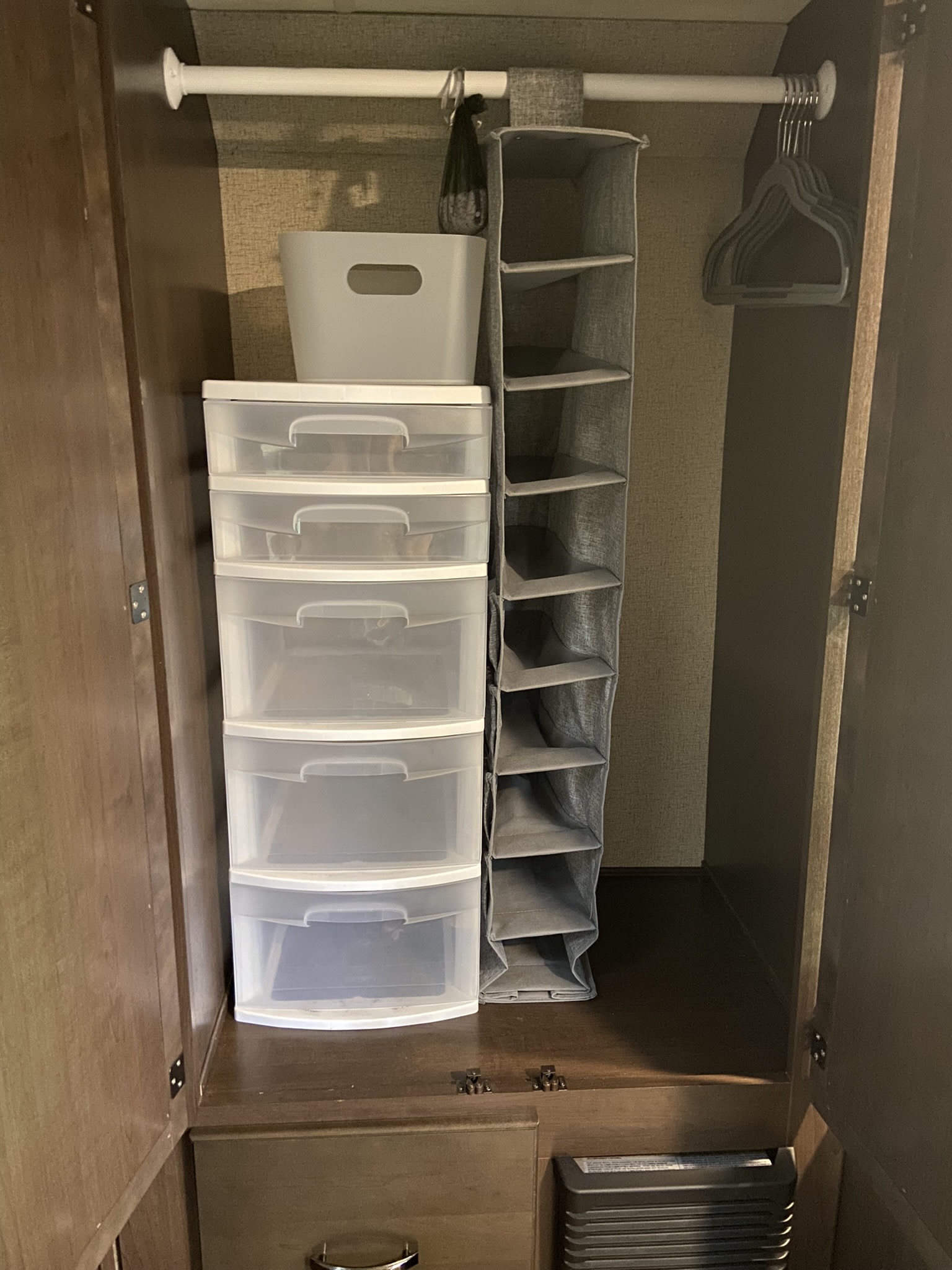 An RV rental closet features clear plastic drawers, a fabric hanging organizer, and hangers for compact storage.. Thor Freedom Elite 2020
