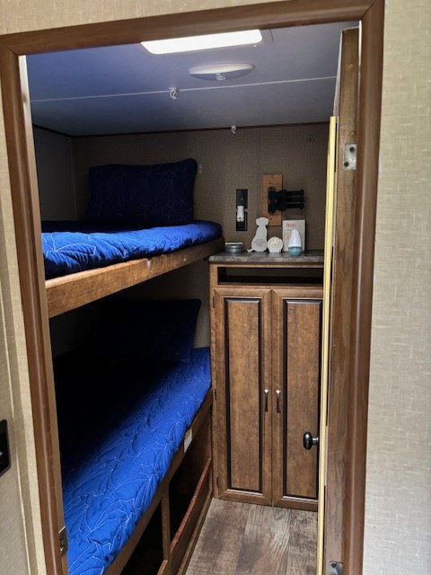Inside an RV rental: comfortable bunk beds with vibrant blue covers and handy storage cabinetry.. Crossroads RV Zinger 2017
