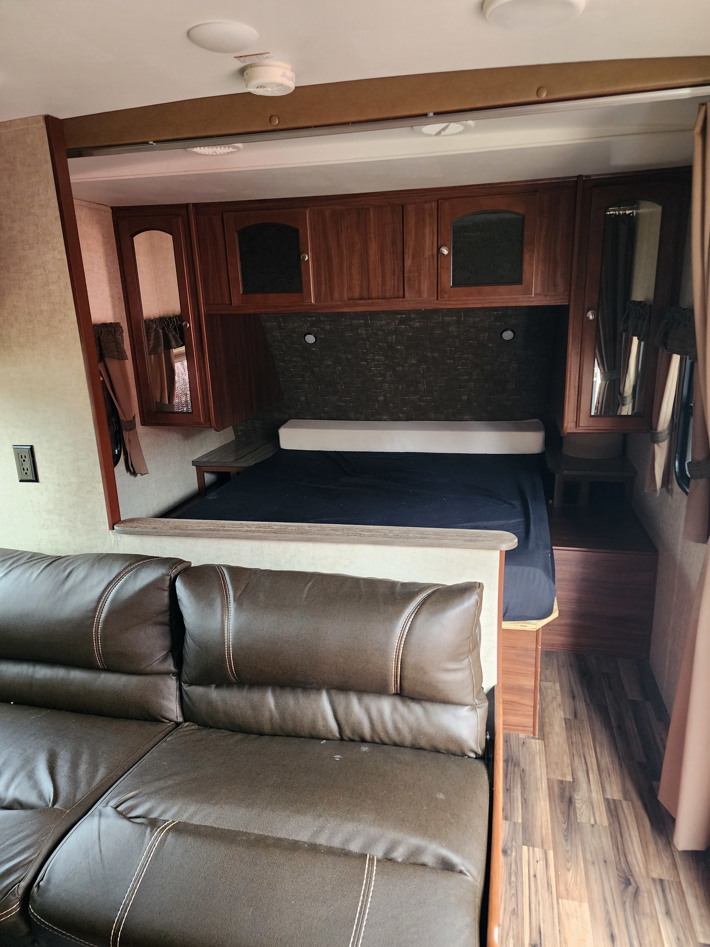 RV rental interior: View of the main living area with a brown sofa and a raised bed area with wooden cabinets.. Heartland RVs North Trail 2016