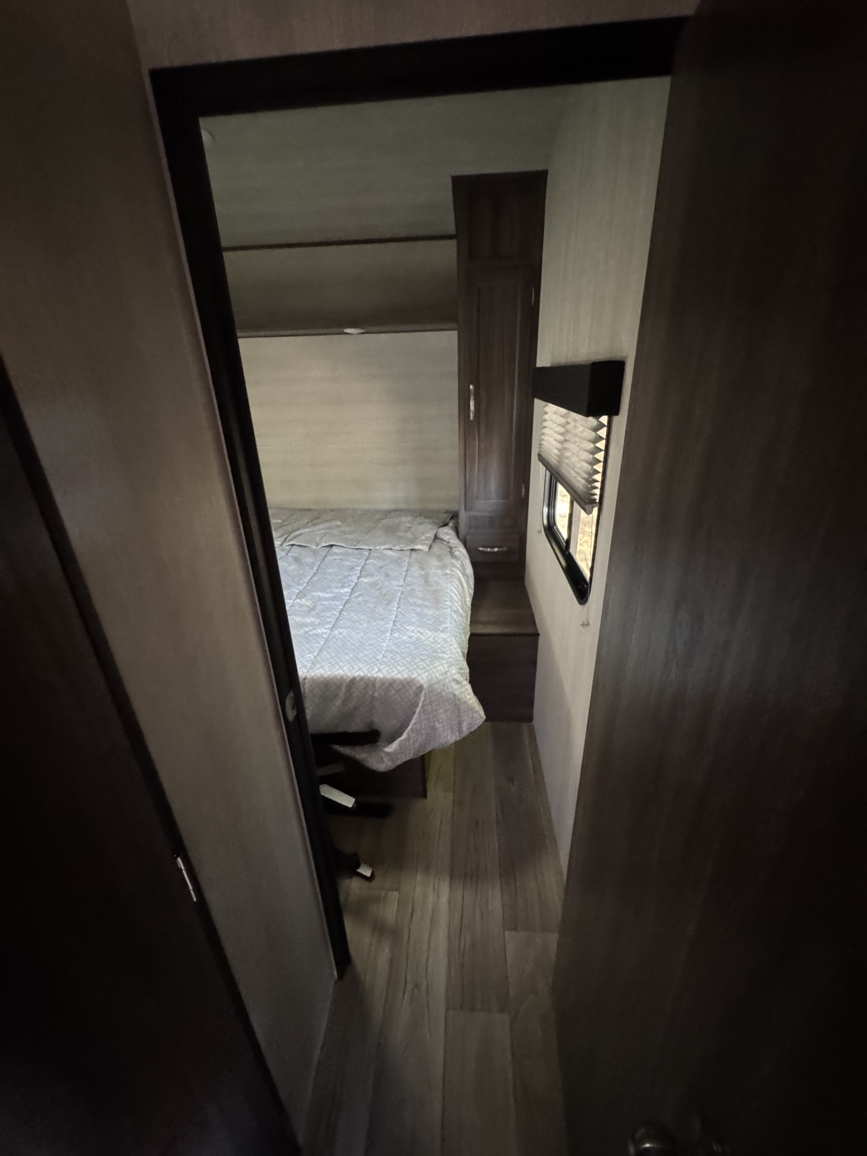 Explore this compact RV rental bedroom, featuring a cozy bed, cabinet, window with blinds, and wood-look flooring.. Genesis Supreme Rv FS2750 2026