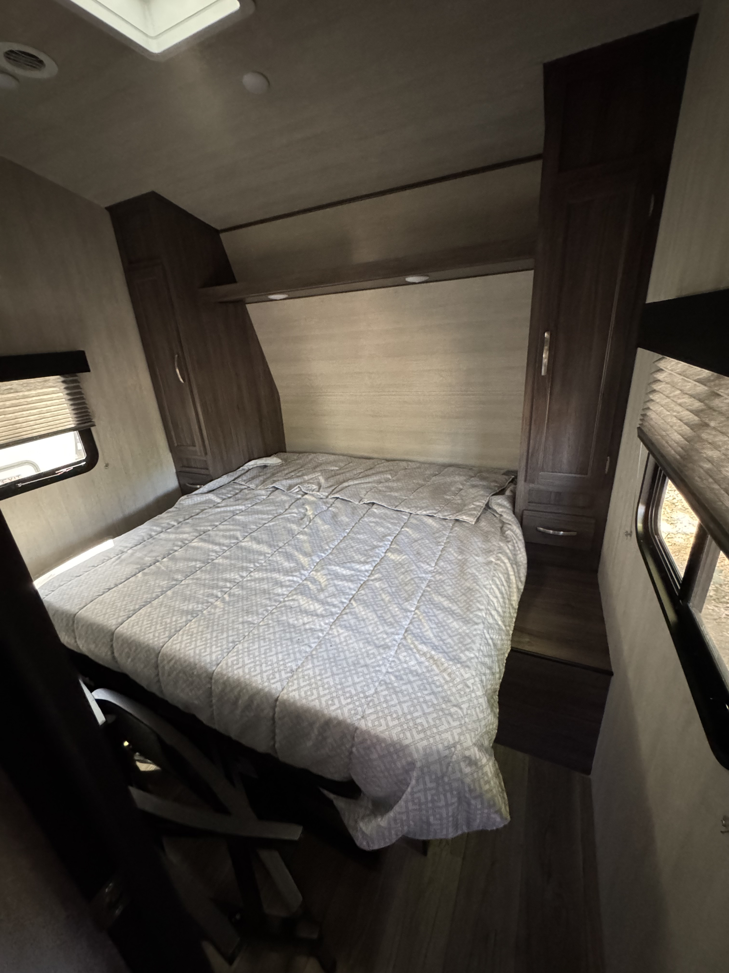 Relax in this RV rental's bedroom, featuring a patterned comforter, built-in storage, and windows for natural light.. Genesis Supreme Rv FS2750 2026