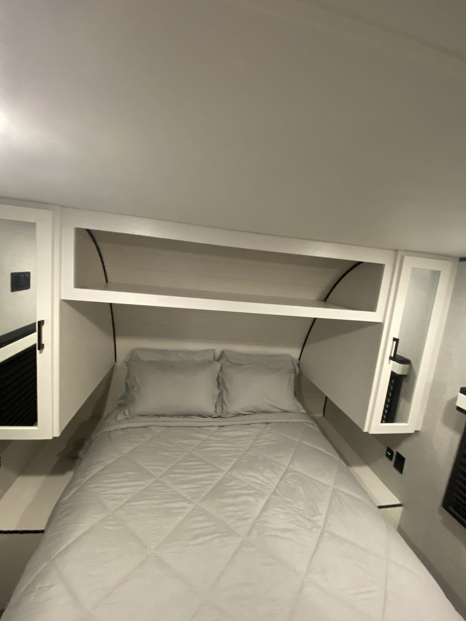 RV rental bedroom with a neat bed, gray quilt, and integrated storage above and beside the bed for a comfortable stay.. Jayco Jay Flight SLX 2025
