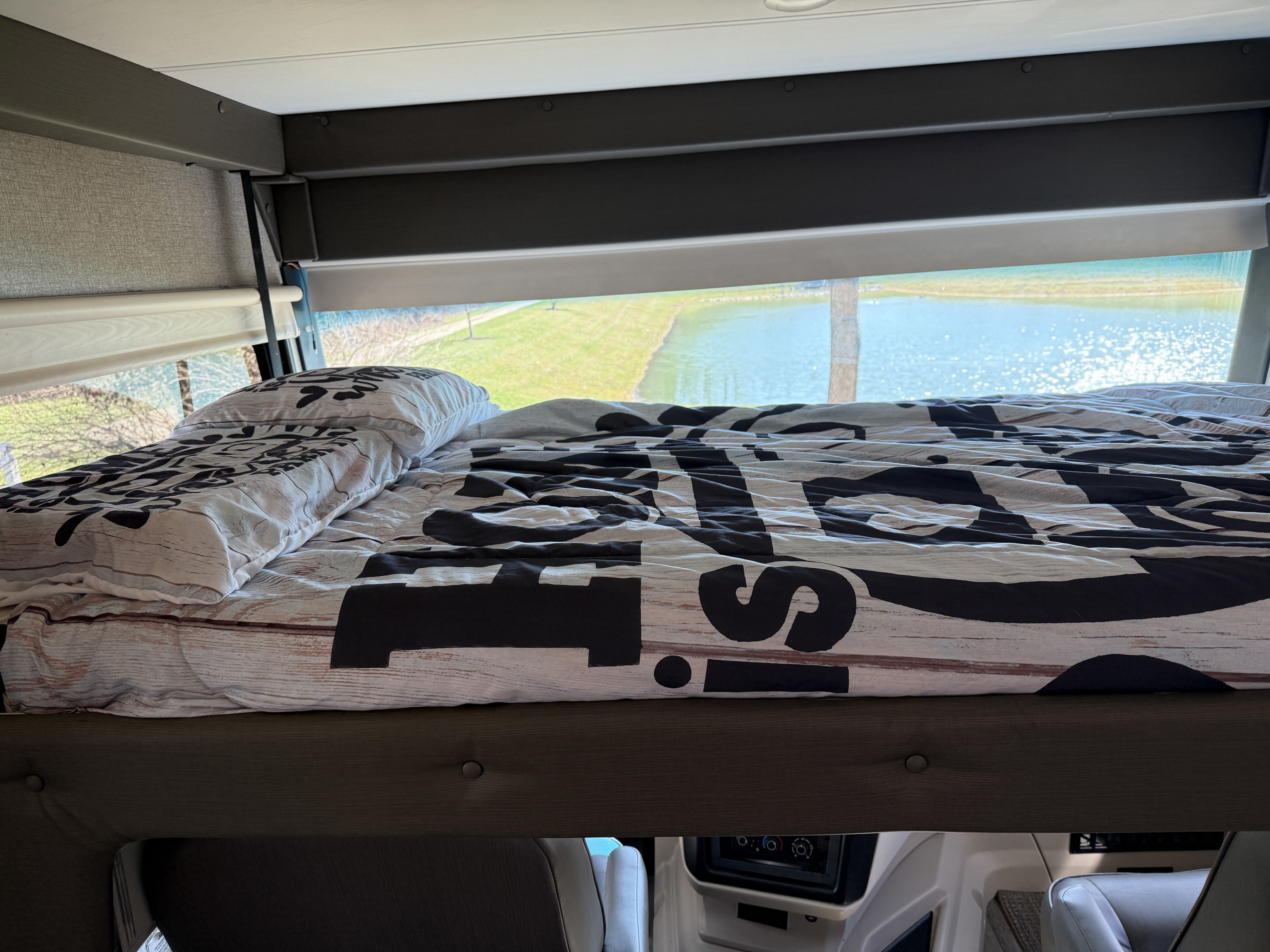 Cozy RV rental bunk bed with scenic water view. Perfect for travel adventures and motorhome comfort, overlooking a lake.. Jayco Precept 2021