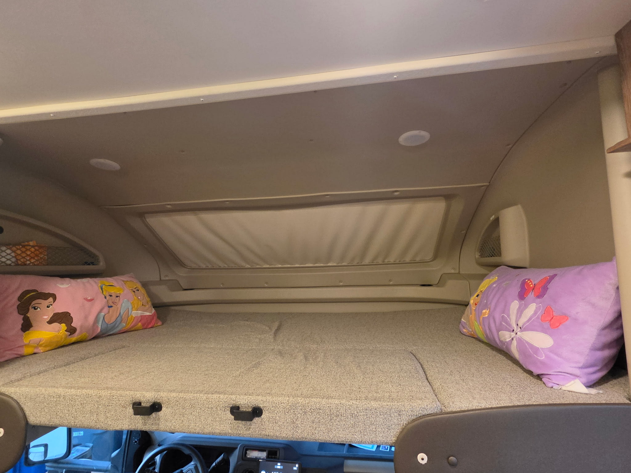RV rental: Overhead bunk bed sleeping area with princess and butterfly pillows, visible dashboard below.. Entegra Coach Odyssey 2022