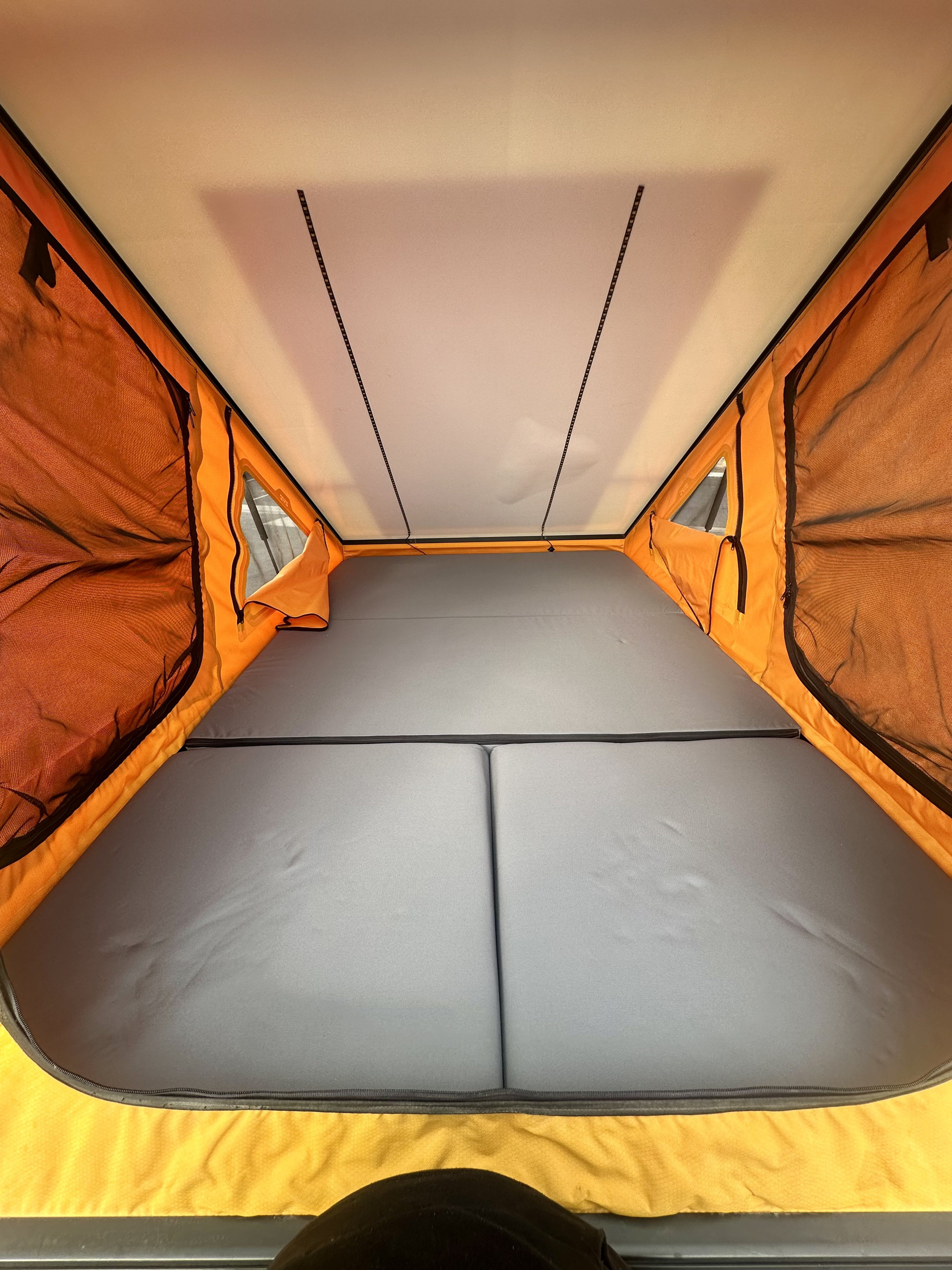 RV rental interior: cozy sleeping area with gray mattress, orange tent walls, and ceiling LED lights. Ideal for camping trips.. Ram Power Wagon 2022