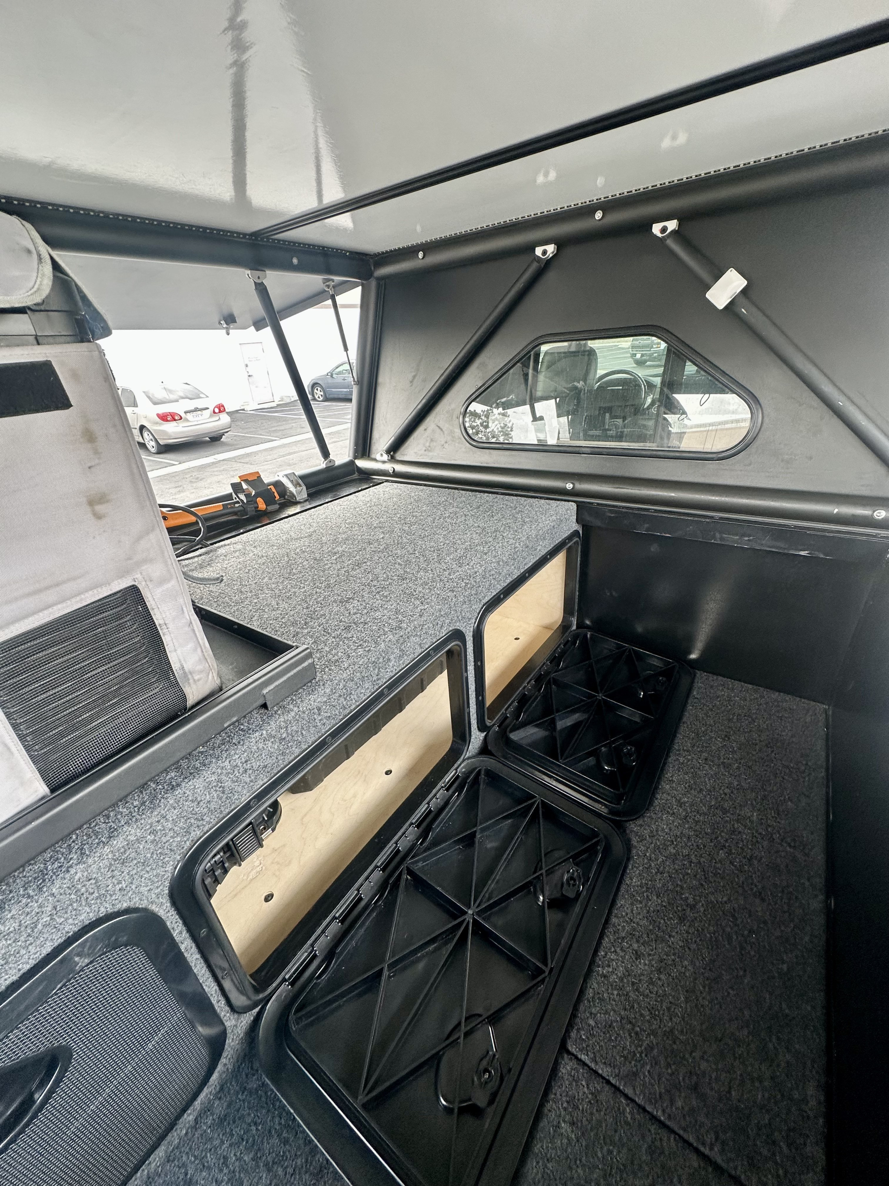 RV rental interior: carpeted sleep platform with built-in storage. LED lighting & side window add comfort to this camper.. Ram Power Wagon 2022