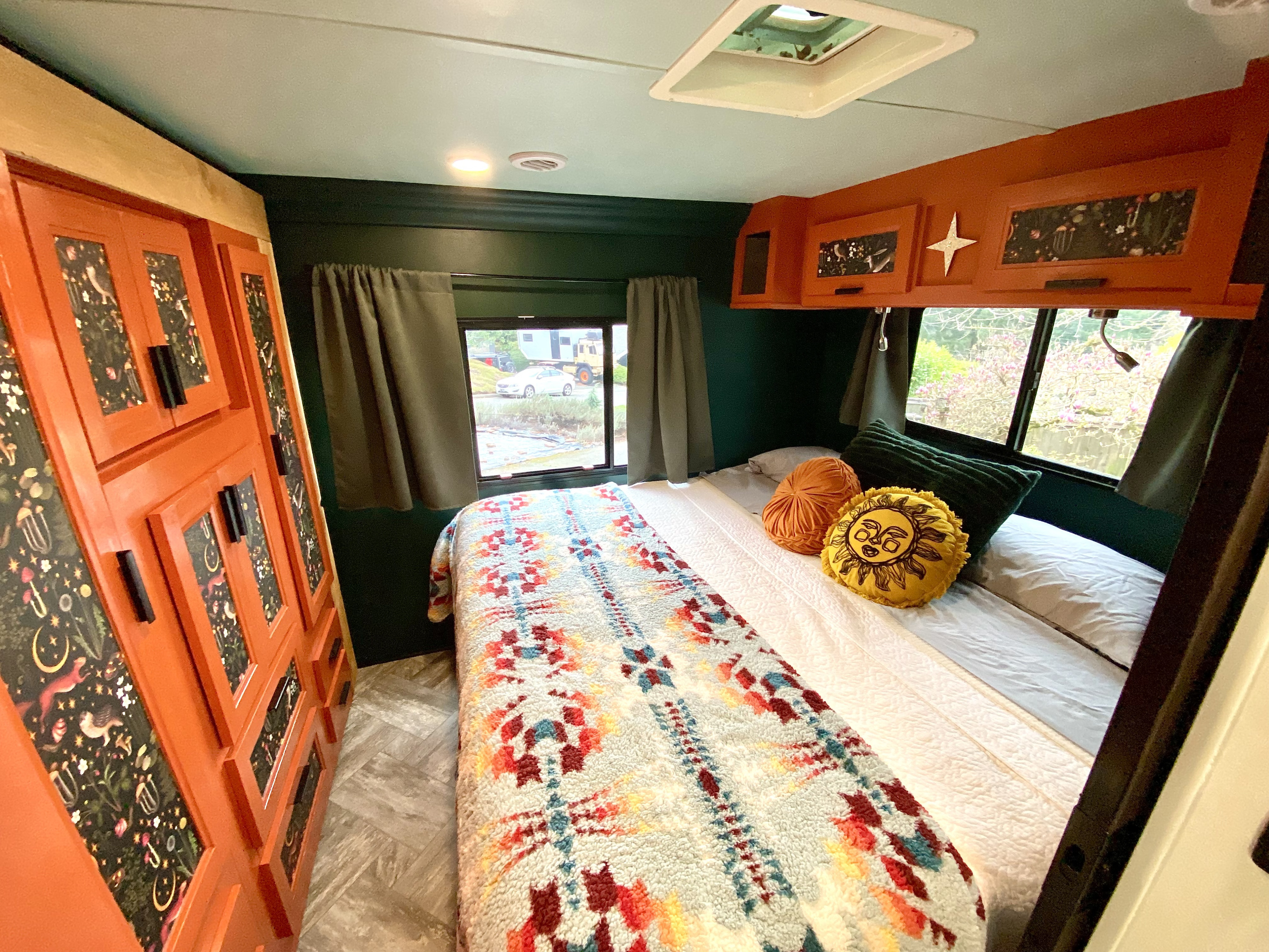 Inside this cozy RV rental bedroom, you'll find vibrant green walls, a colorful patterned quilt, and unique orange cabinets.. Forest River Sunseeker LE 2022