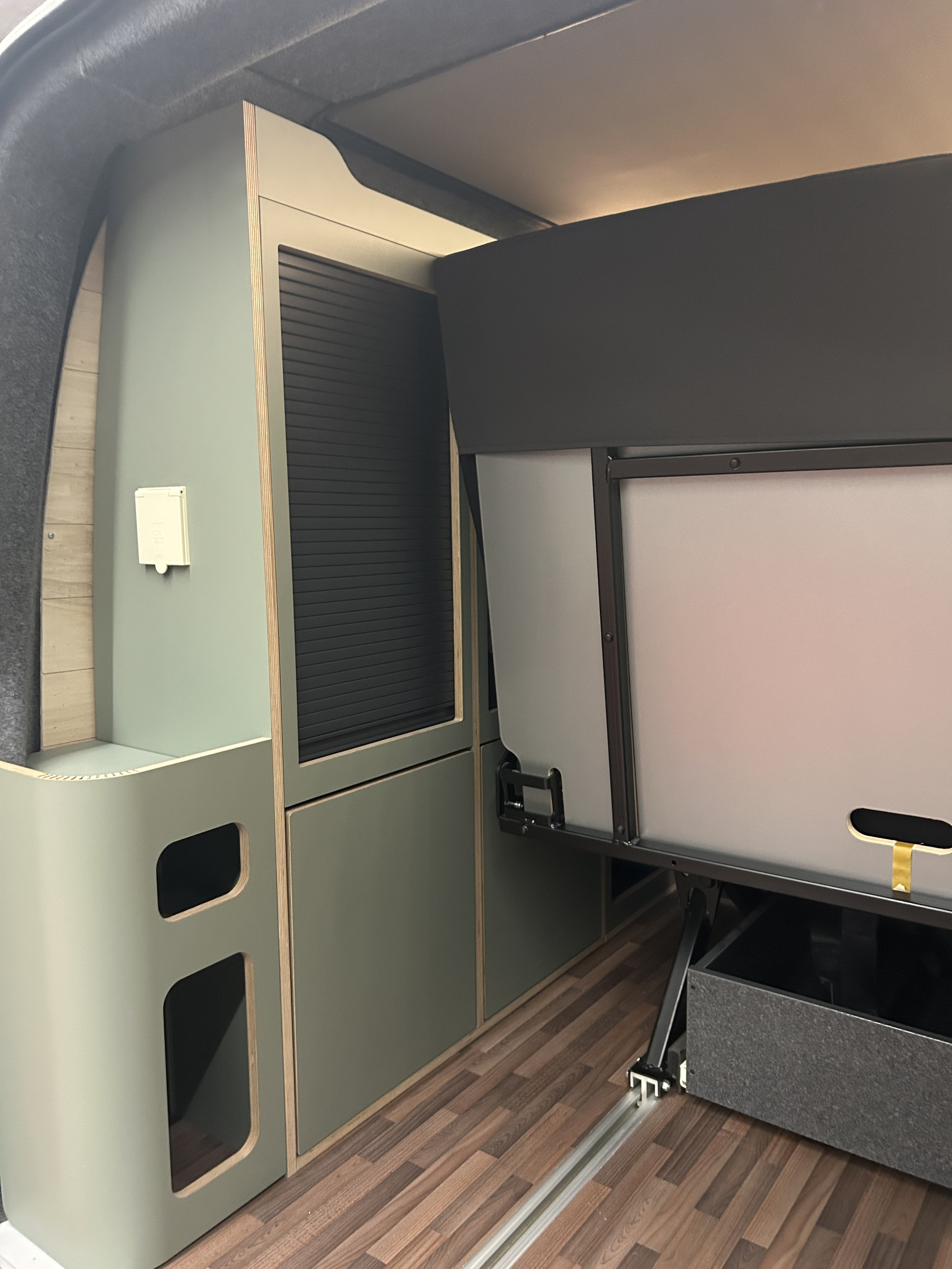 RV rental interior with custom sage cabinets, smart storage, and a convertible bed/table for functional space.. Volkswagen T6 transporter 2021