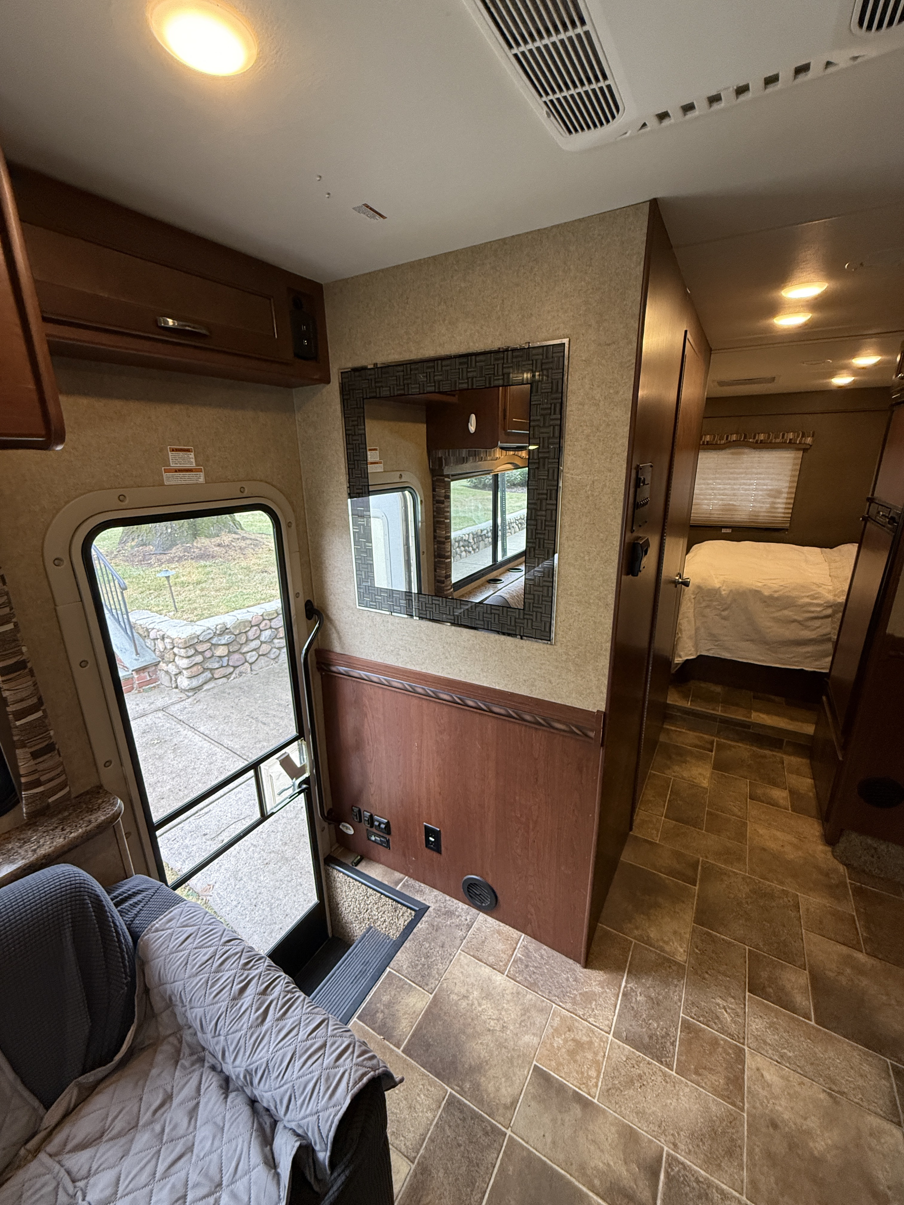 This inviting RV rental interior features the main entrance, a living area, mirror, and a cozy bedroom in the back.. Thor Chateau 2016