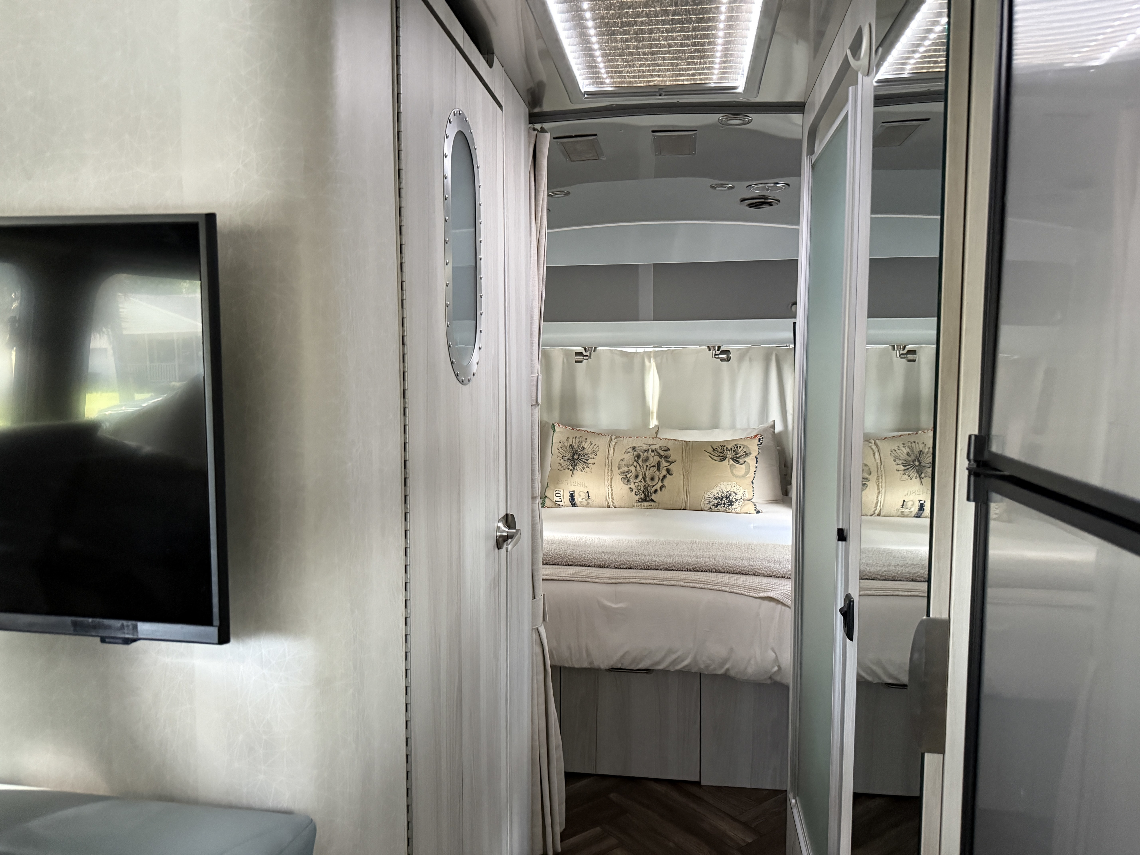 Discover this clean and modern RV rental interior. A cozy bedroom with patterned pillows awaits, perfect for your next road trip.. Airstream International 2021
