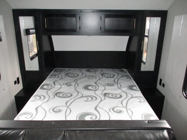 RV rental bedroom: white & gray patterned mattress on bed, black overhead cabinets, & side windows.. Forest River Cherokee Grey Wolf 2022