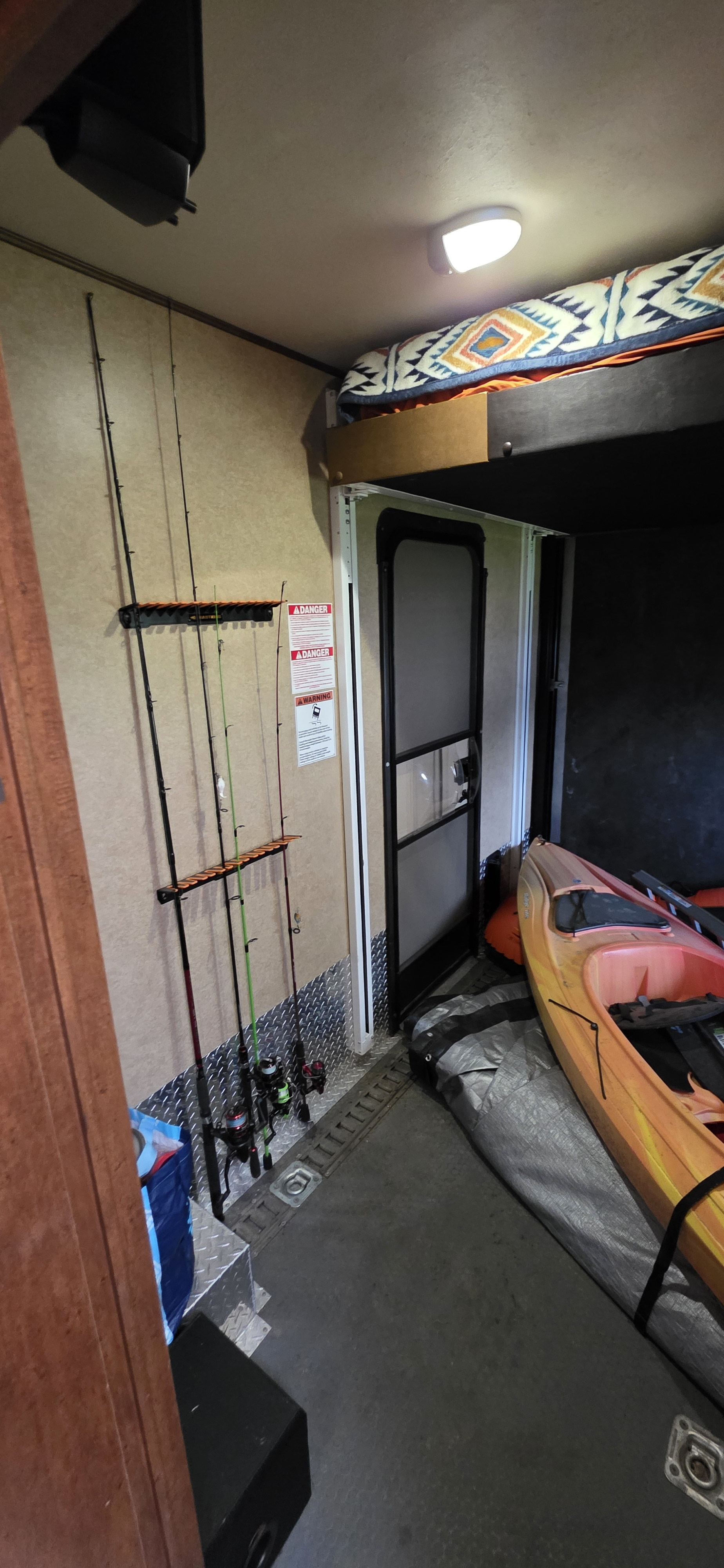 RV rental interior featuring fishing rods on a rack, a kayak, and a bunk bed for outdoor gear storage.. Forest River Xlr Thunrderbolt 2014