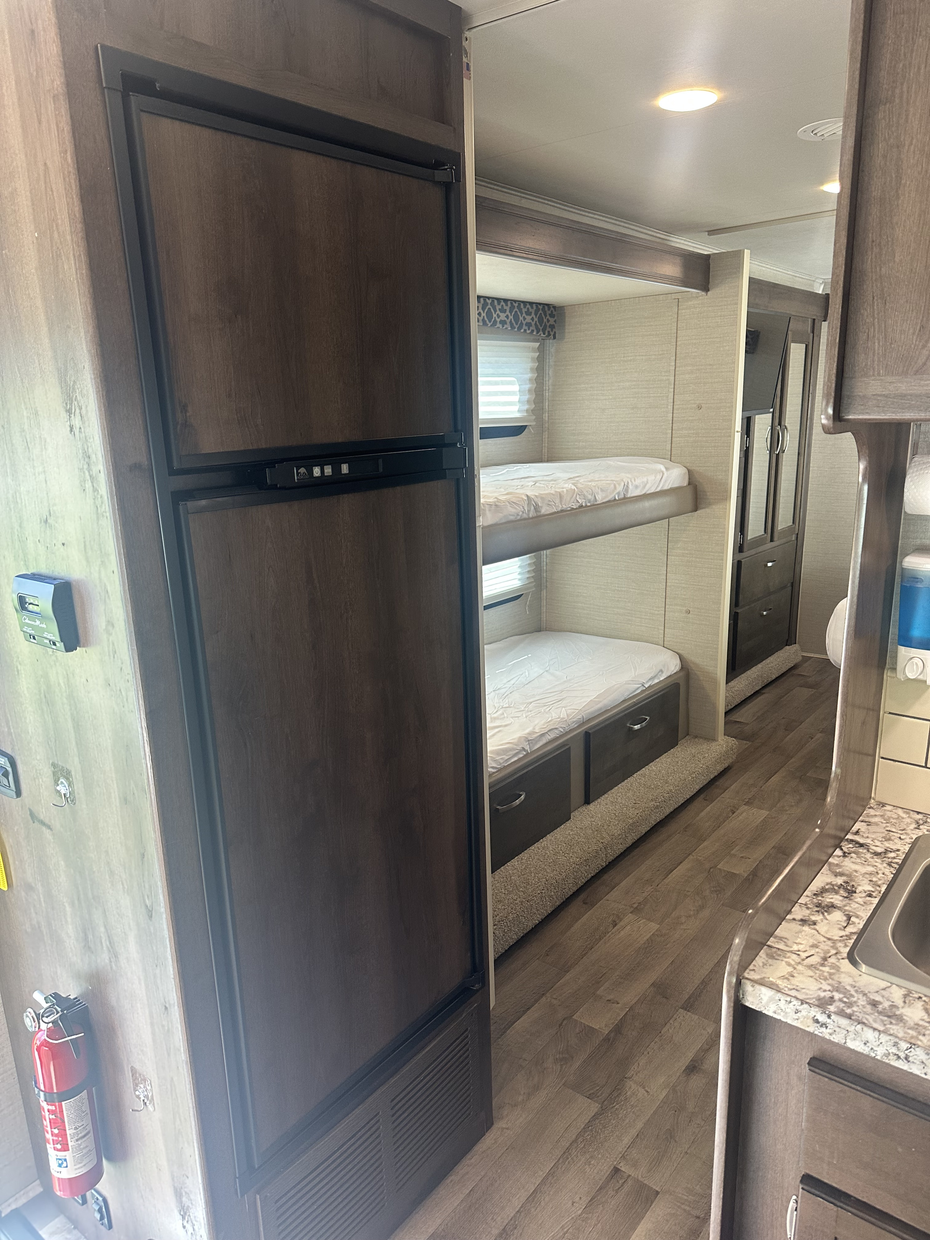 RV rental interior: compact living space with bunk beds, refrigerator, and kitchen for your travel adventures.. Jayco Redhawk 2019