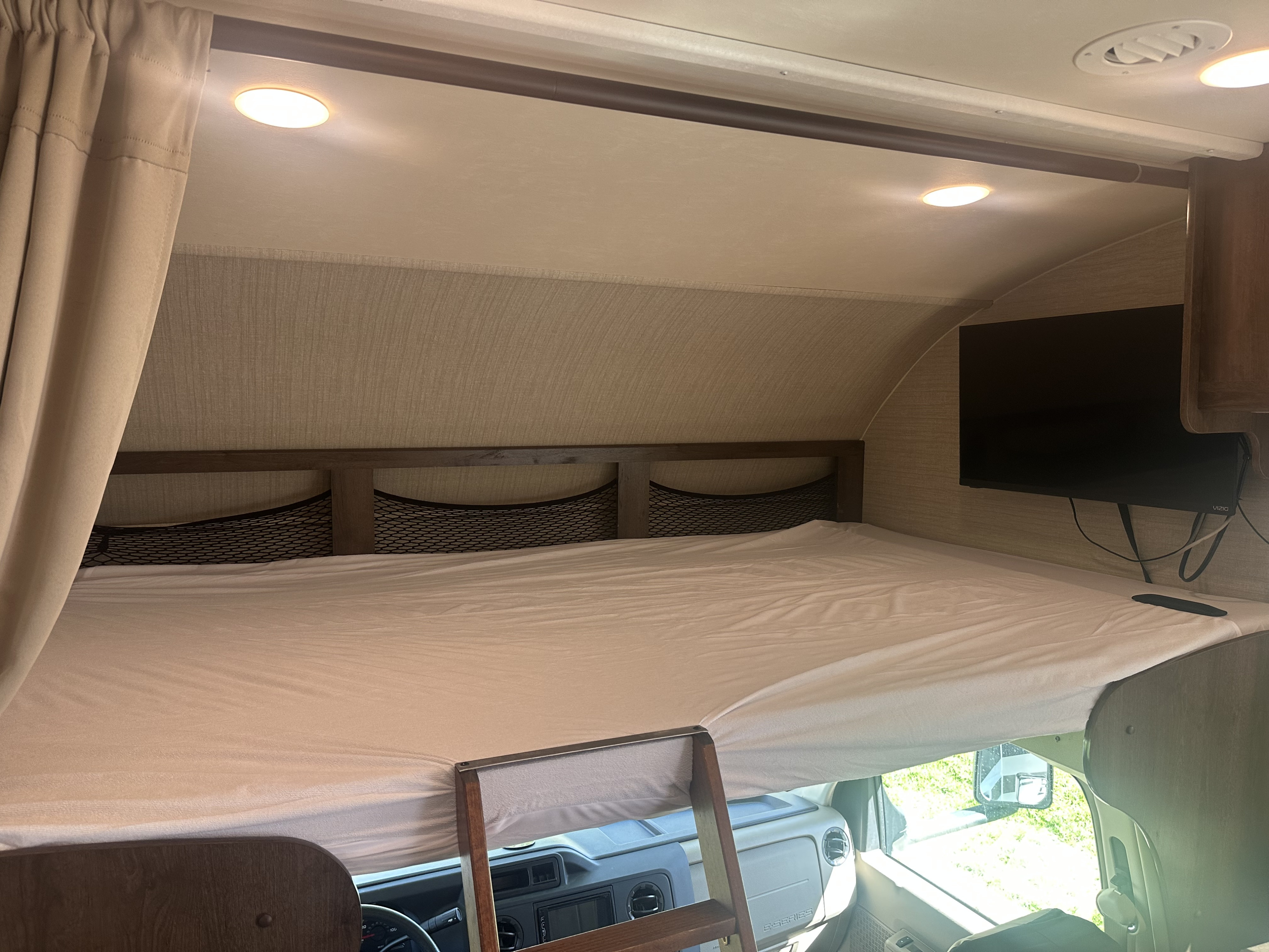 This RV rental's over-cab bunk bed offers a cozy sleeping area with mesh storage, a TV, and recessed lighting.. Jayco Redhawk 2019