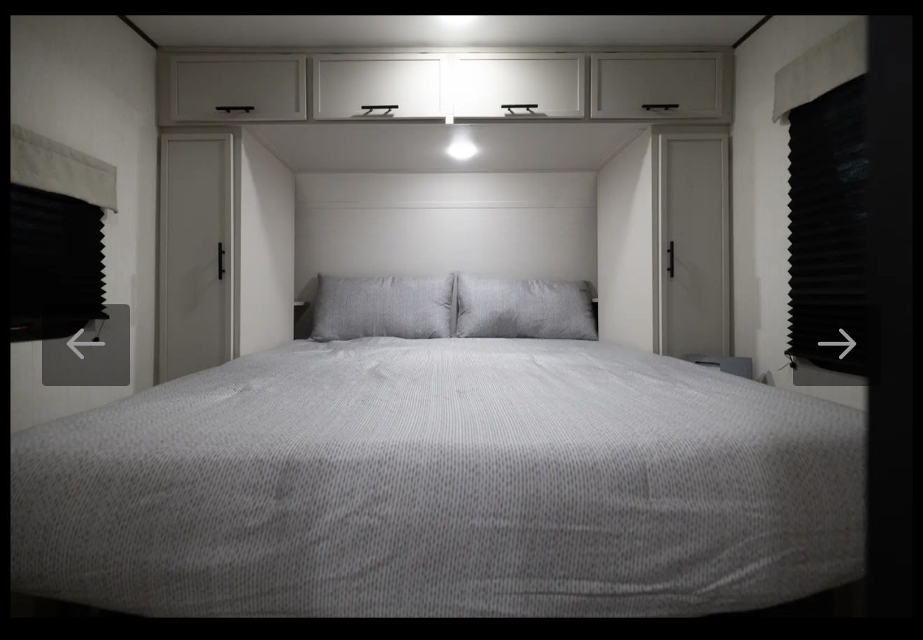 Cozy RV rental bedroom with modern overhead cabinets, compact wardrobes, and comfortable striped bedding.. Prime time 25RBS 2026