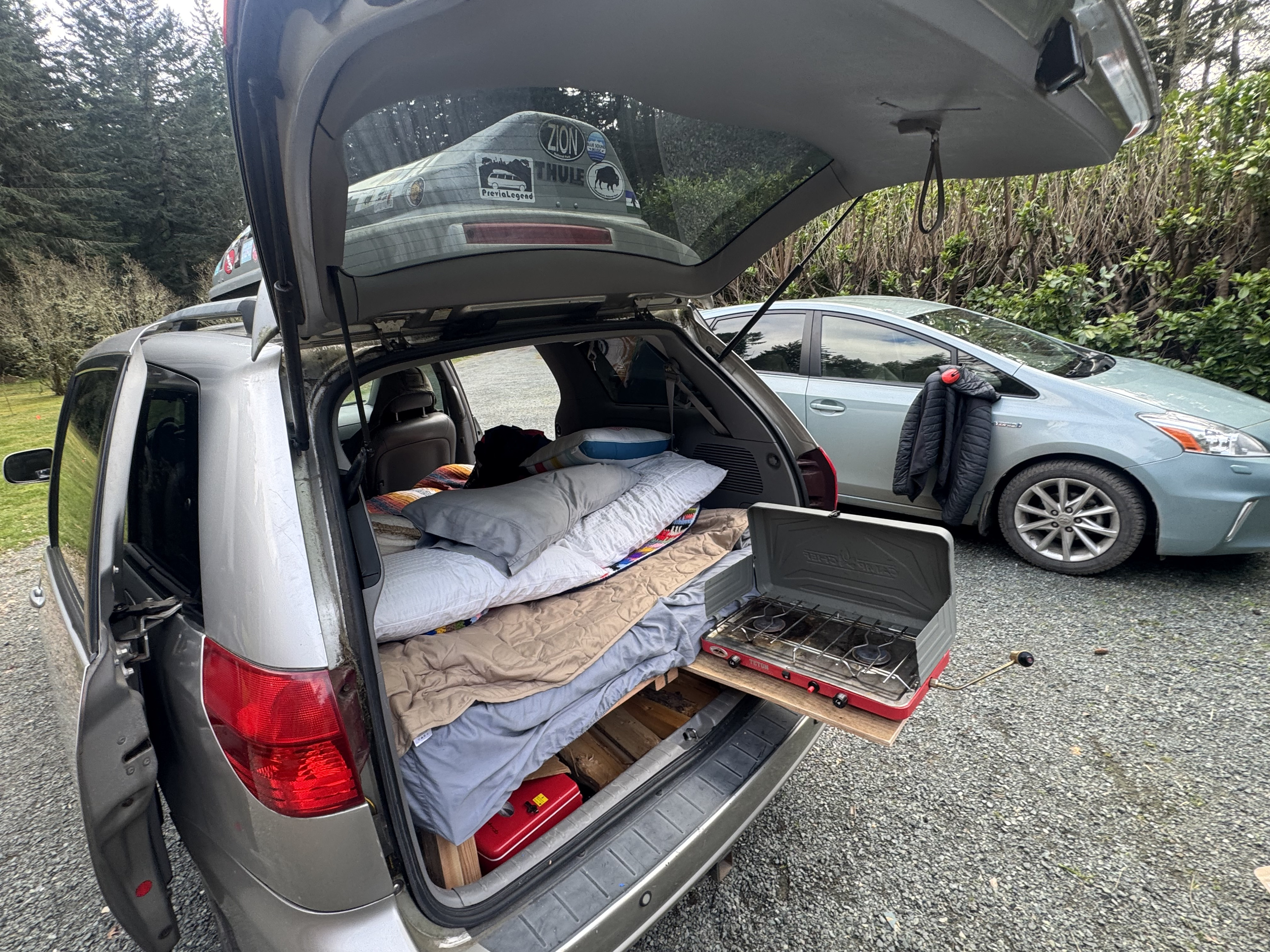 Creative car camping setup. See inside this RV rental alternative with a bed & camp stove pulled from the open tailgate.. Toyota 2004 Sienna Limited XLE Conversion 2004