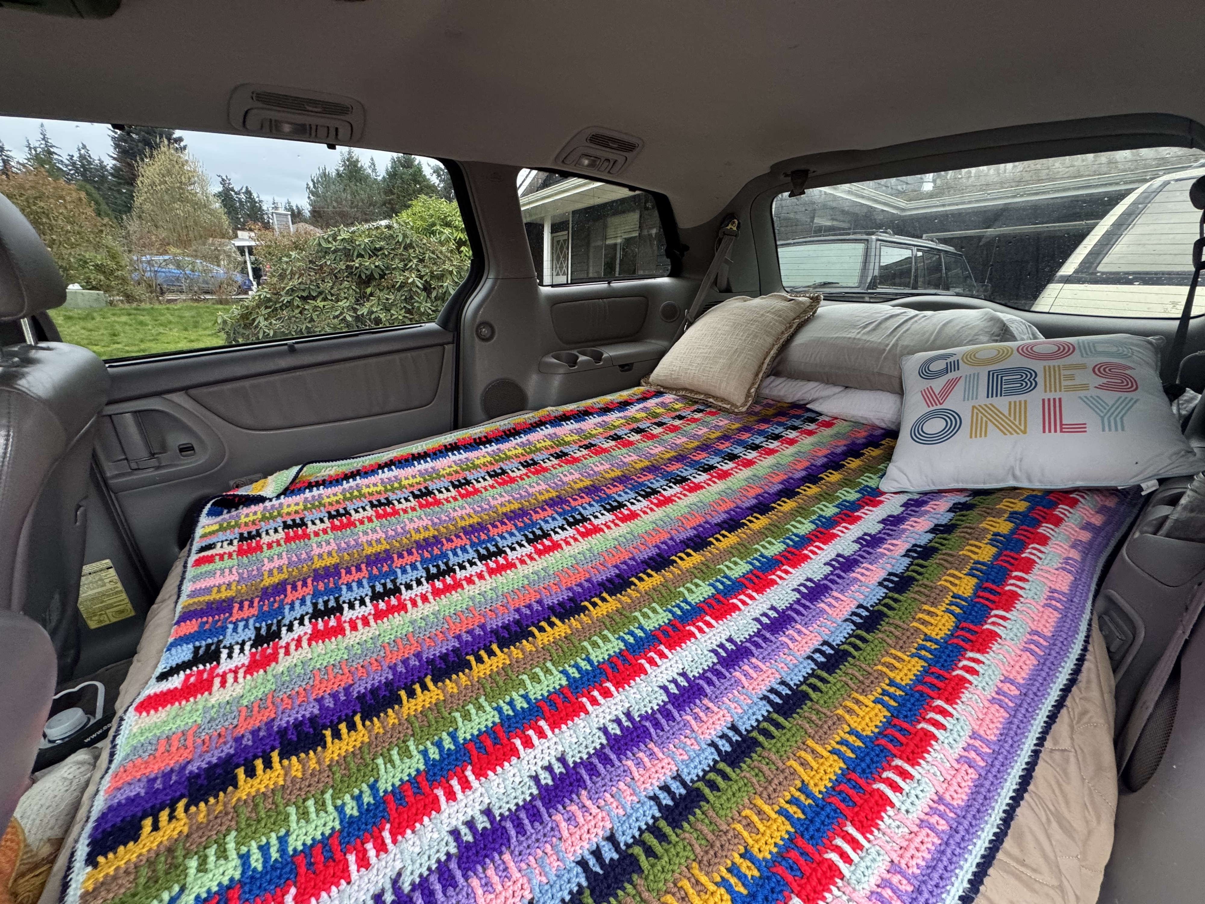 Colorful crochet blanket & pillows on a bed in a vehicle, ready for adventure. Perfect for an RV rental alternative!. Toyota 2004 Sienna Limited XLE Conversion 2004