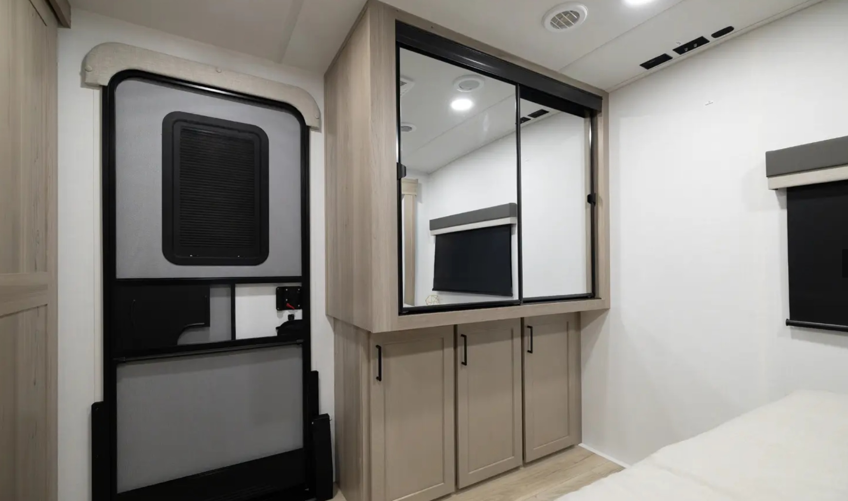 RV rental interior: A modern door, mirrored cabinets, and a glimpse of a bed and window in a compact space.. Forest River Flagstaff Super Lite 2025