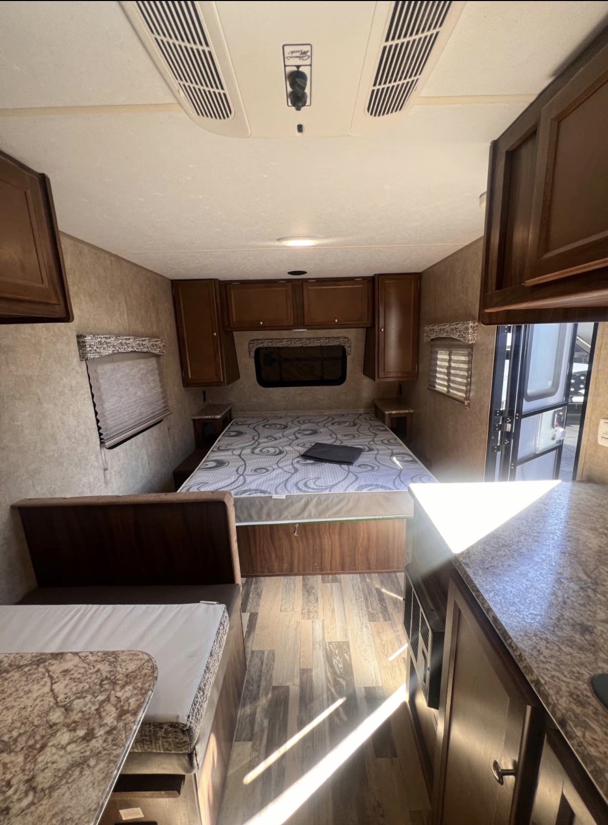 Spacious RV rental interior with bedroom, dinette, and kitchen. Features include wood flooring, overhead storage, and AC.. Forest River Viking 2018