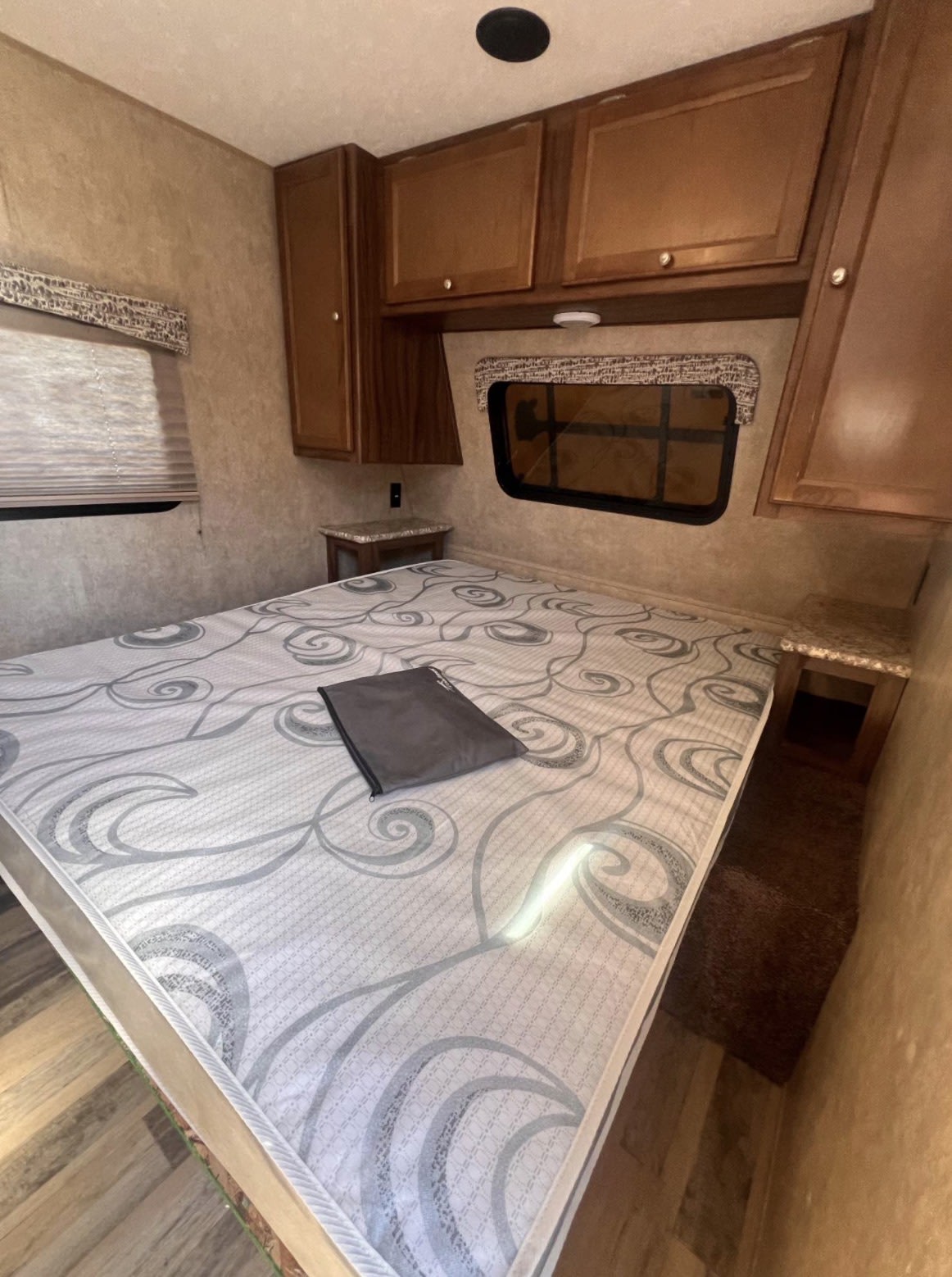Cozy RV rental bedroom features a patterned queen mattress, overhead cabinets, and bedside tables for comfort.. Forest River Viking 2018