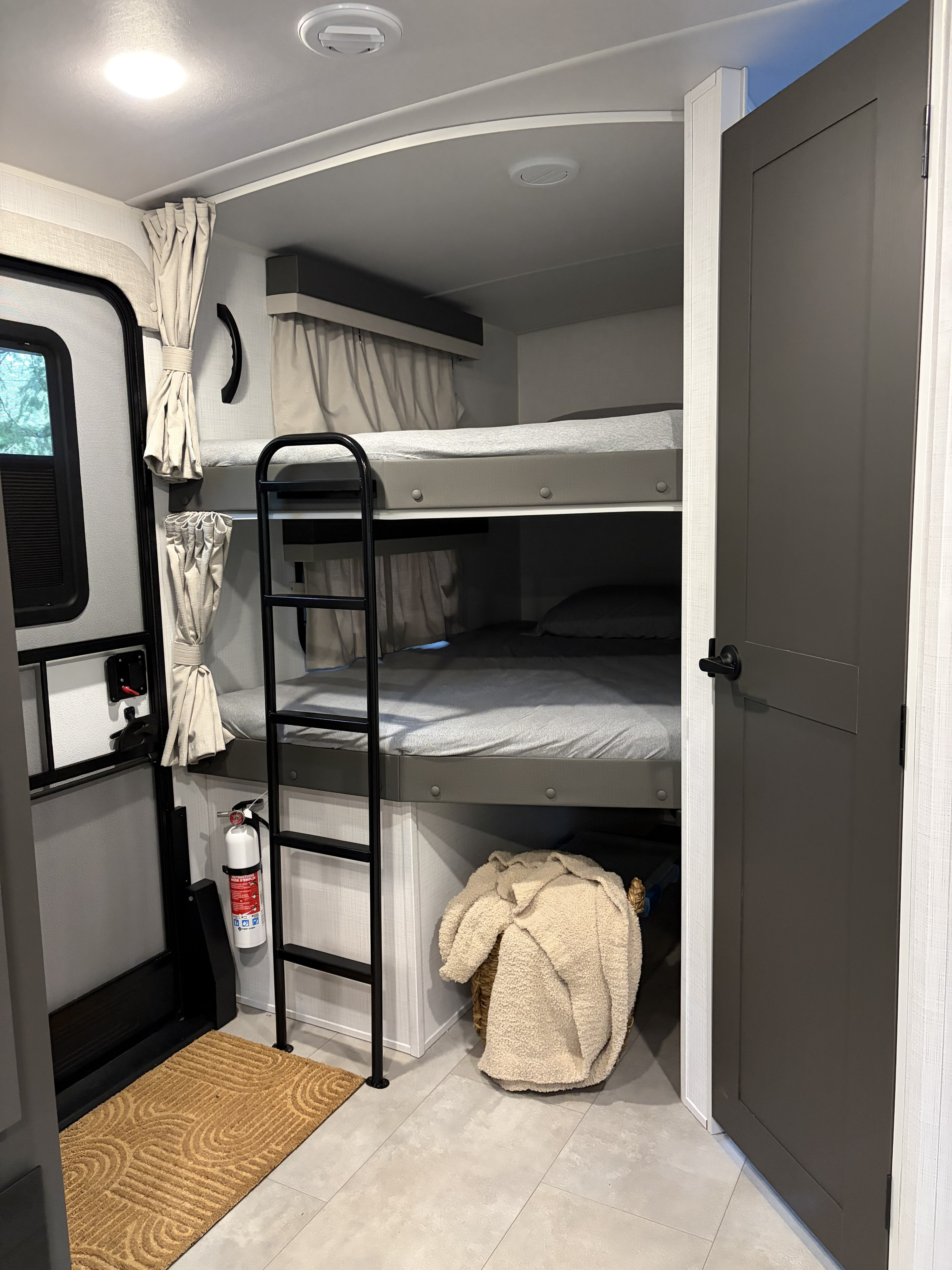 Cozy rv rental interior with bunk beds, an entry door, and a fire extinguisher for safety.. Forest River Flagstaff Super Lite 2025