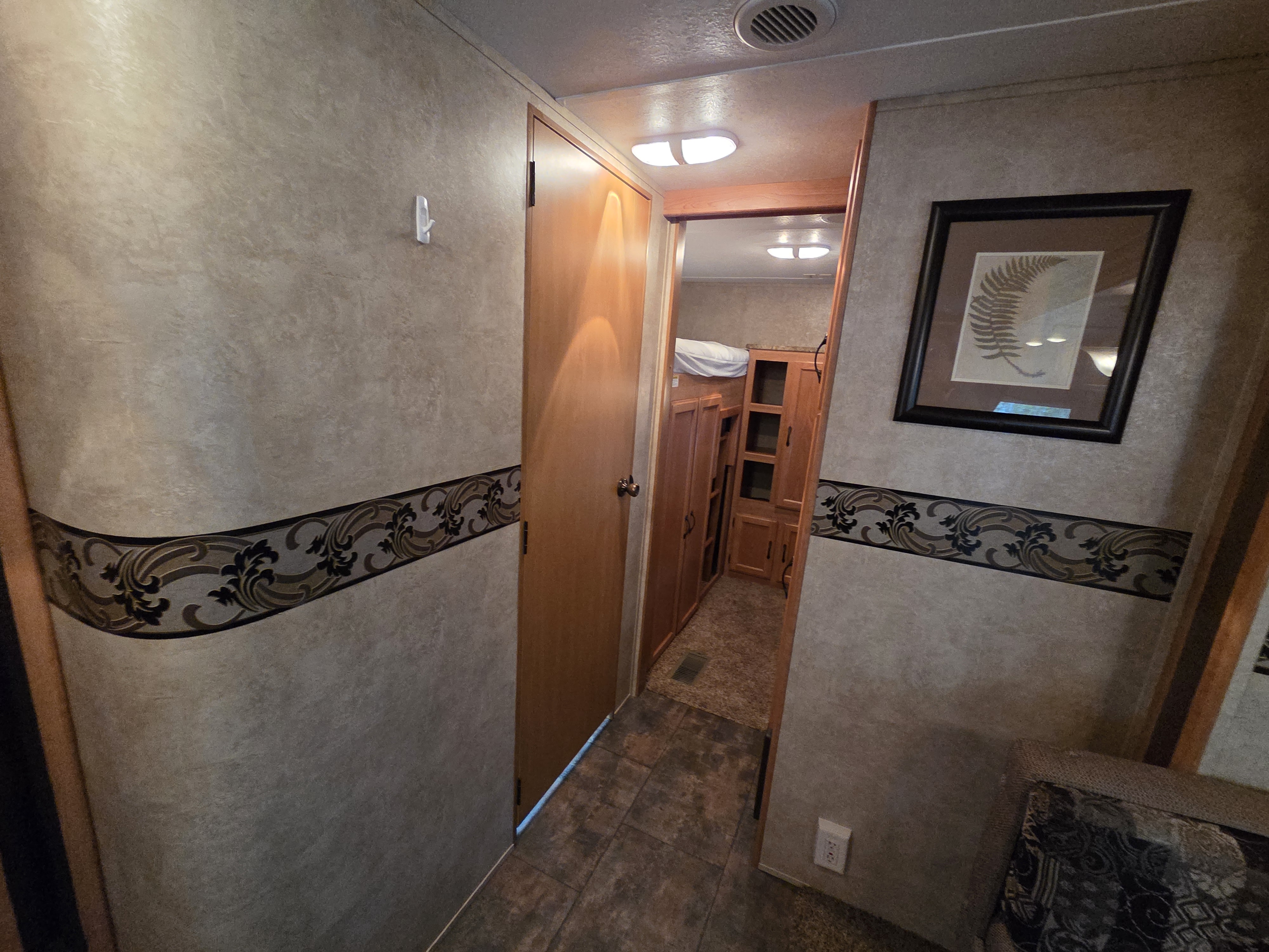 RV rental: Interior hallway showcasing patterned wallpaper, a framed picture, and a view into a bunk bed area.. Keystone RV Sprinter 2011